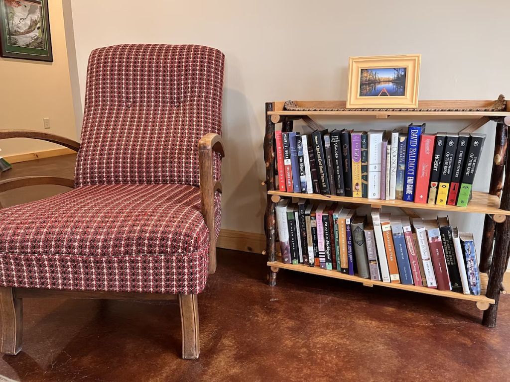A chair and ottoman are next to a bookshelf filled with books.