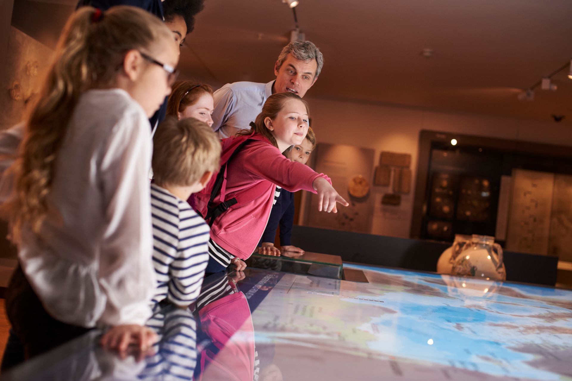 A group of people are looking at a map on a table in a museum.