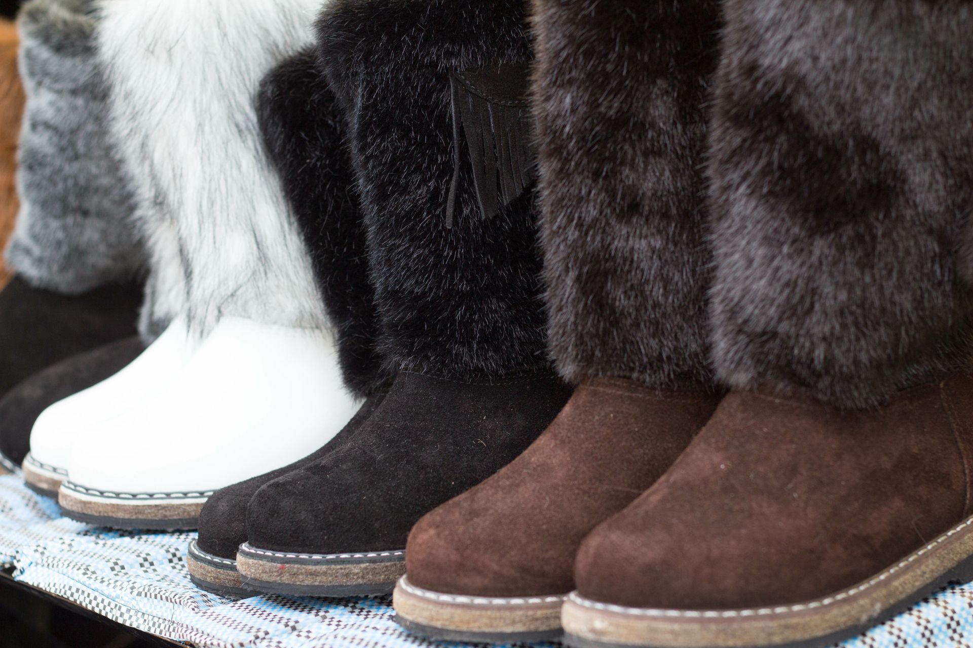 A row of furry boots are lined up on a table.