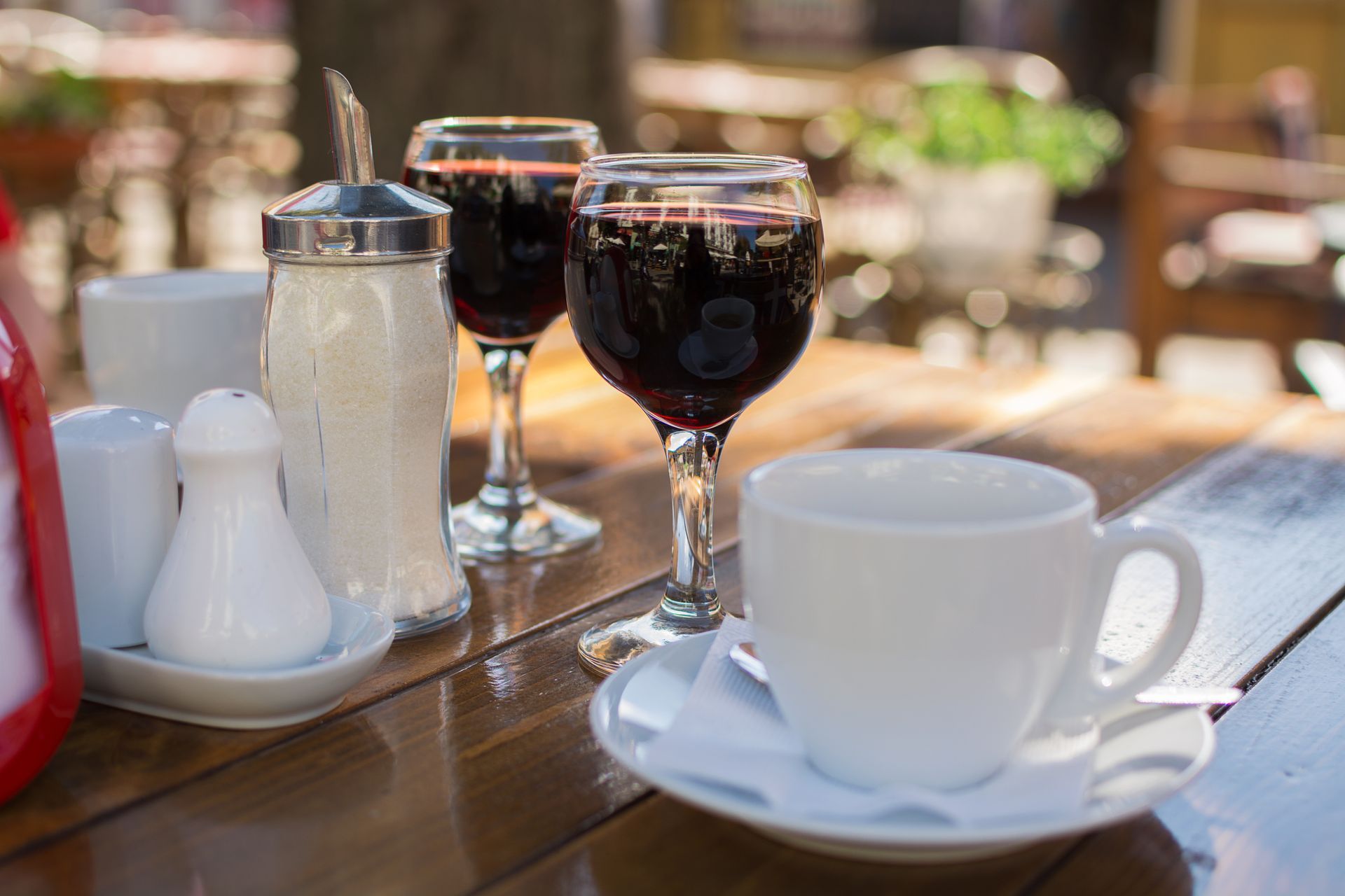 Two glasses of wine and a cup of coffee on a wooden table.