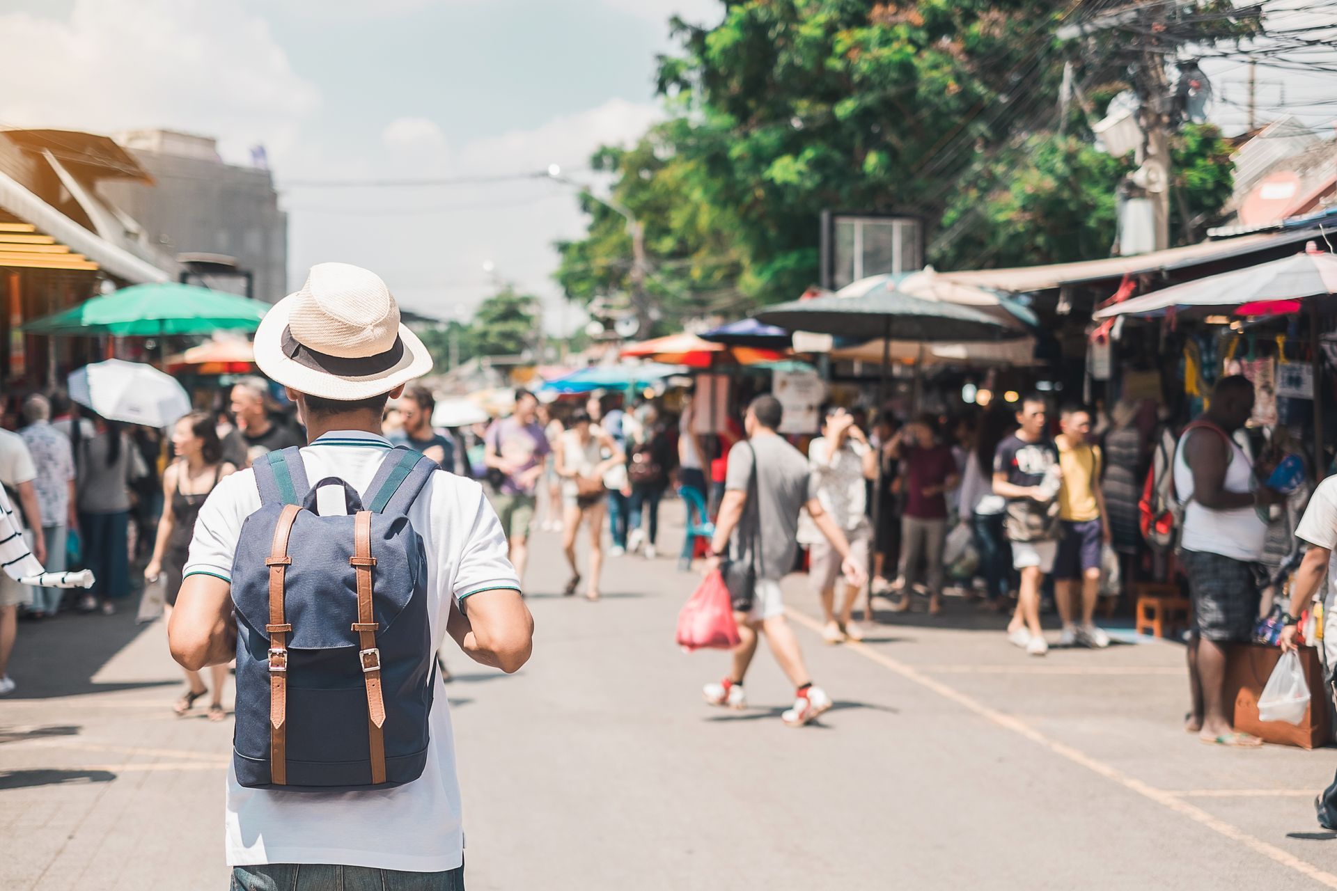 A man with a backpack is walking down a crowded street.