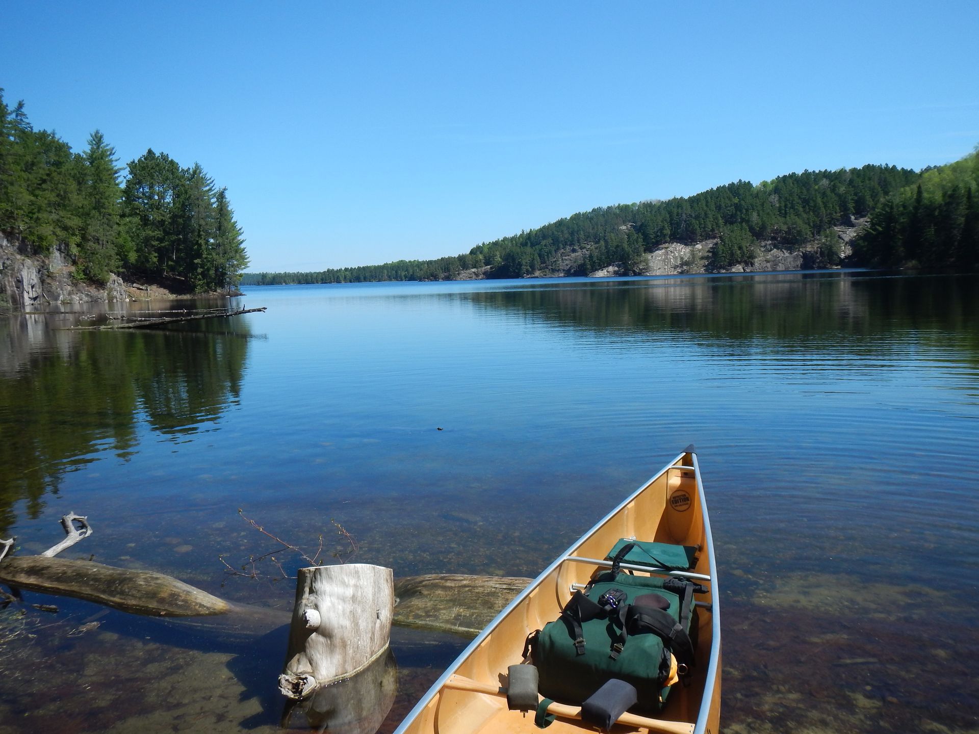 A canoe is sitting on the shore of a lake