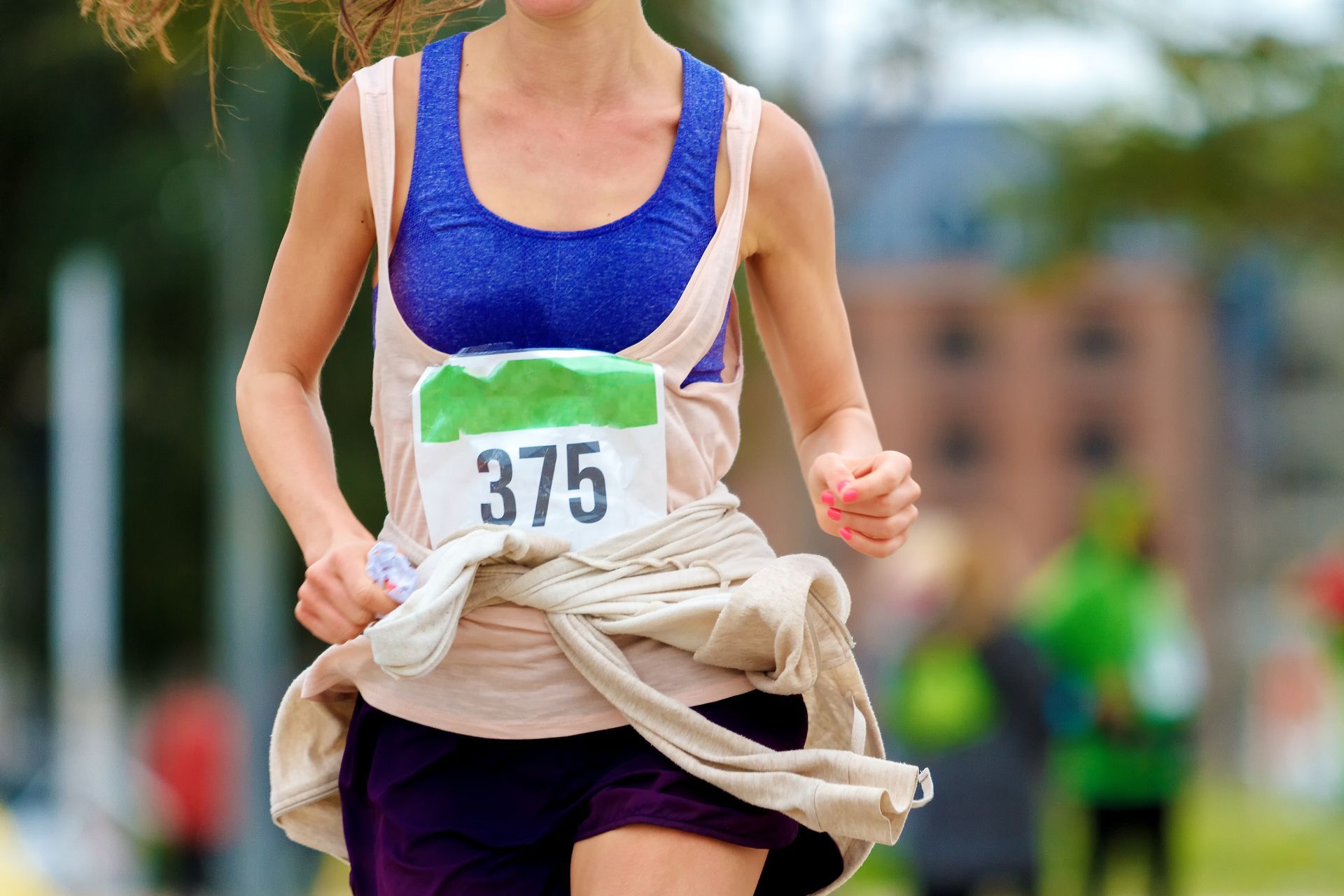 A woman is running in a race with the number 375 on her shirt.