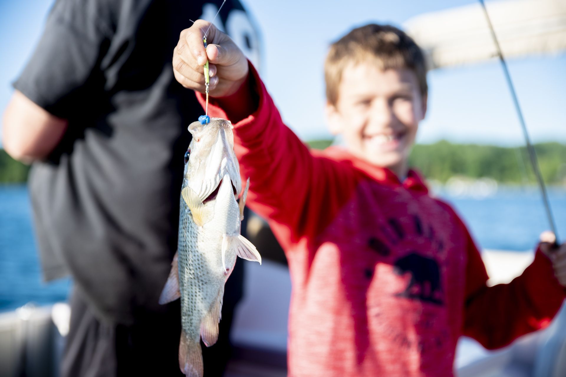 A young boy is holding a fish on a hook.