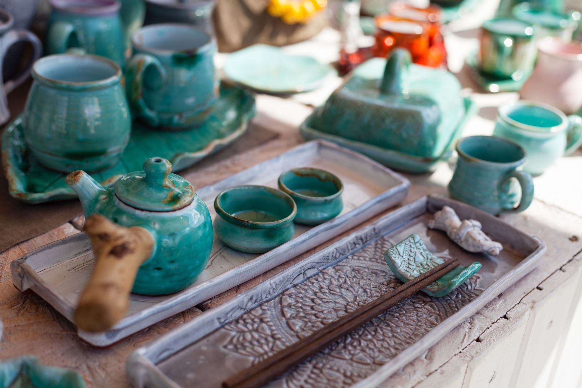 A table topped with a variety of ceramics including a teapot and cups.