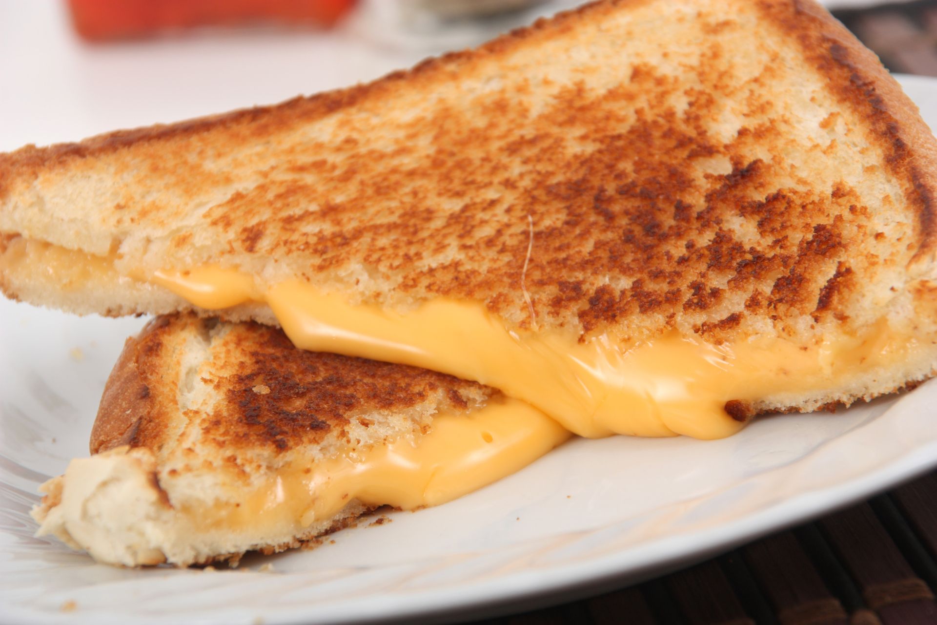 A grilled cheese sandwich is cut in half on a white plate.