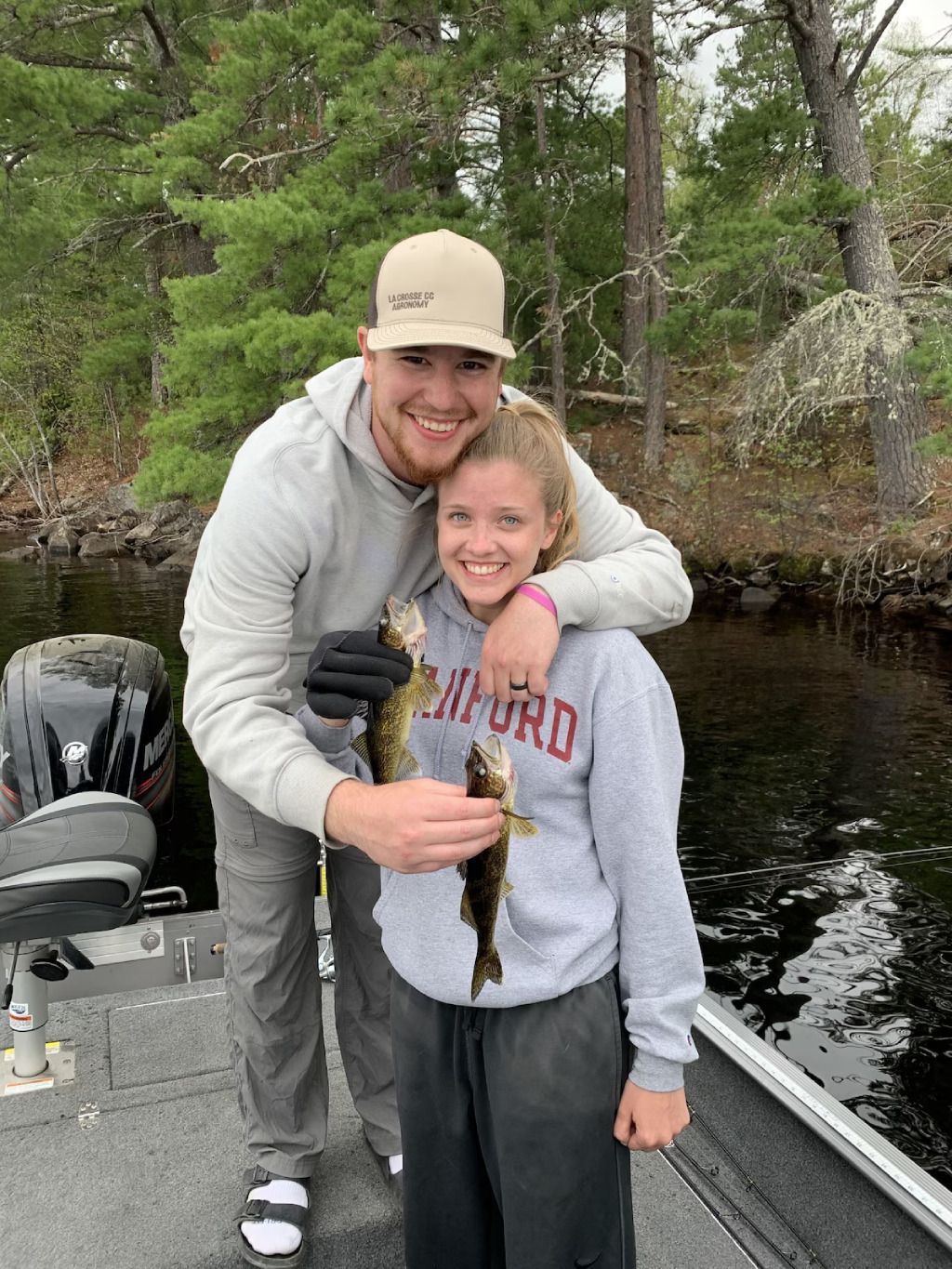 A man and a girl are standing next to a boat holding a fish.