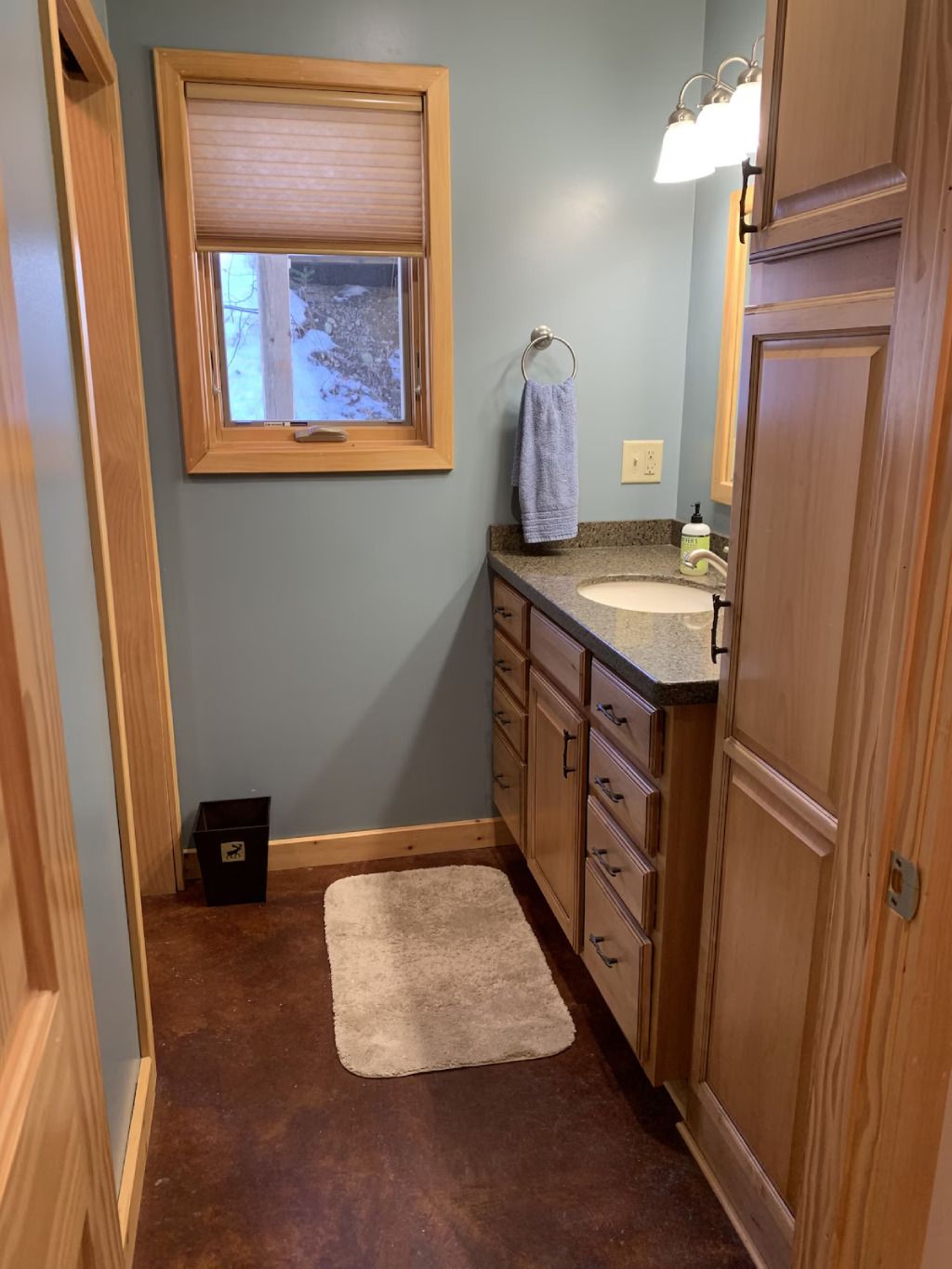 A bathroom with a sink , cabinets , and a window.