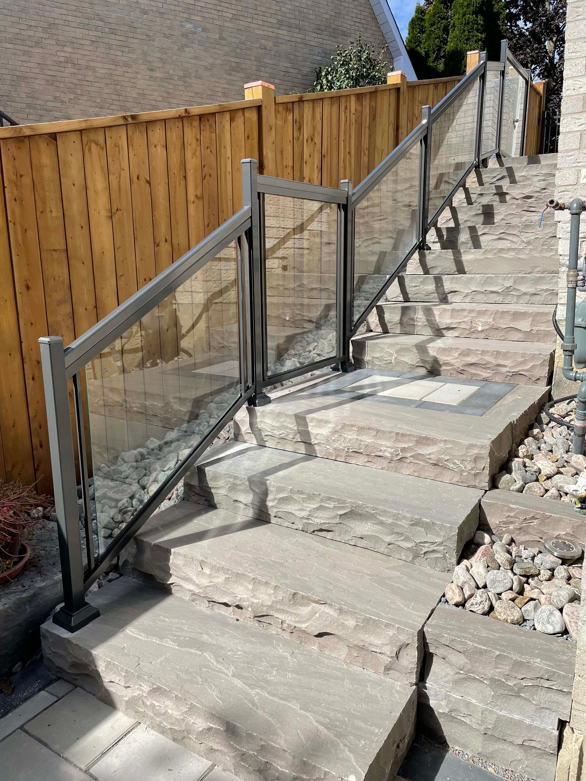 A set of stairs with a glass railing and a wooden fence.