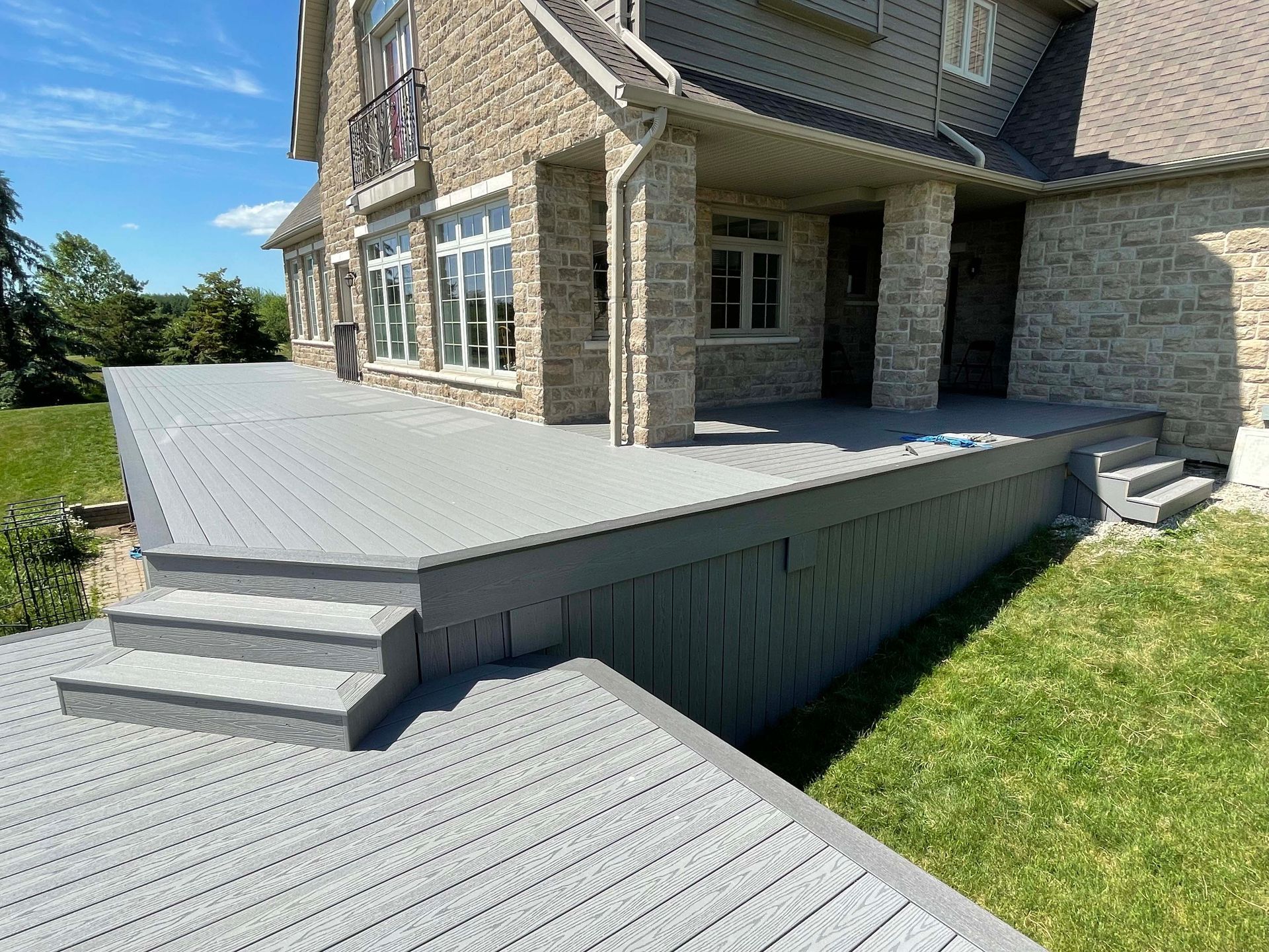 A large brick house with a large deck and stairs in front of it.