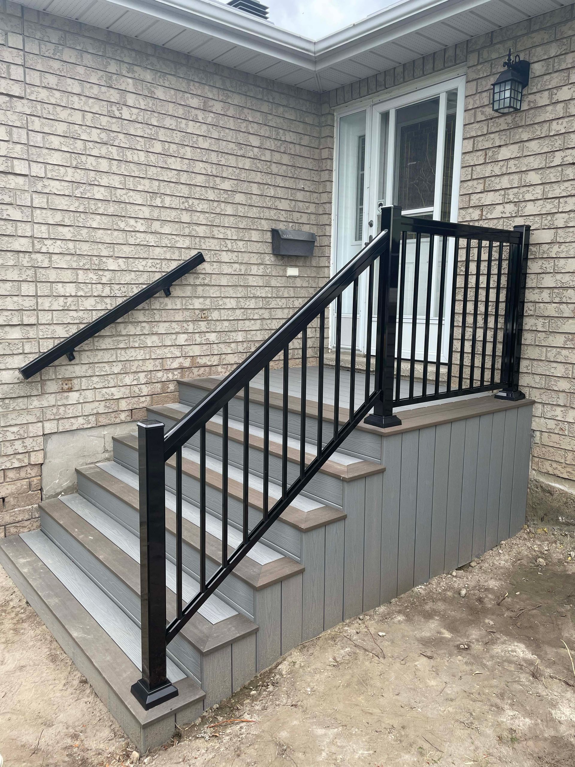 A brick house with stairs and a black railing