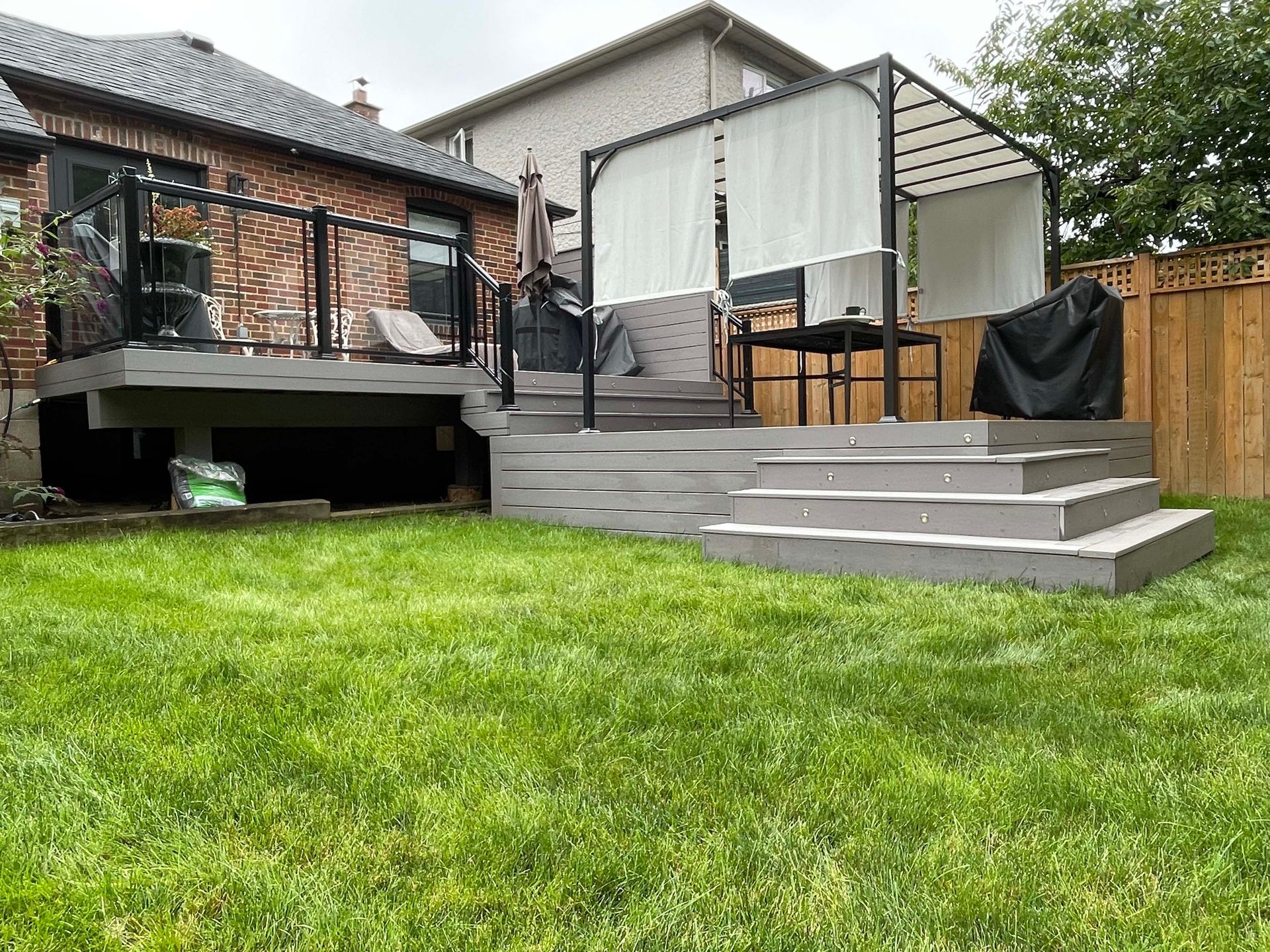 A backyard with a deck and stairs in front of a house.