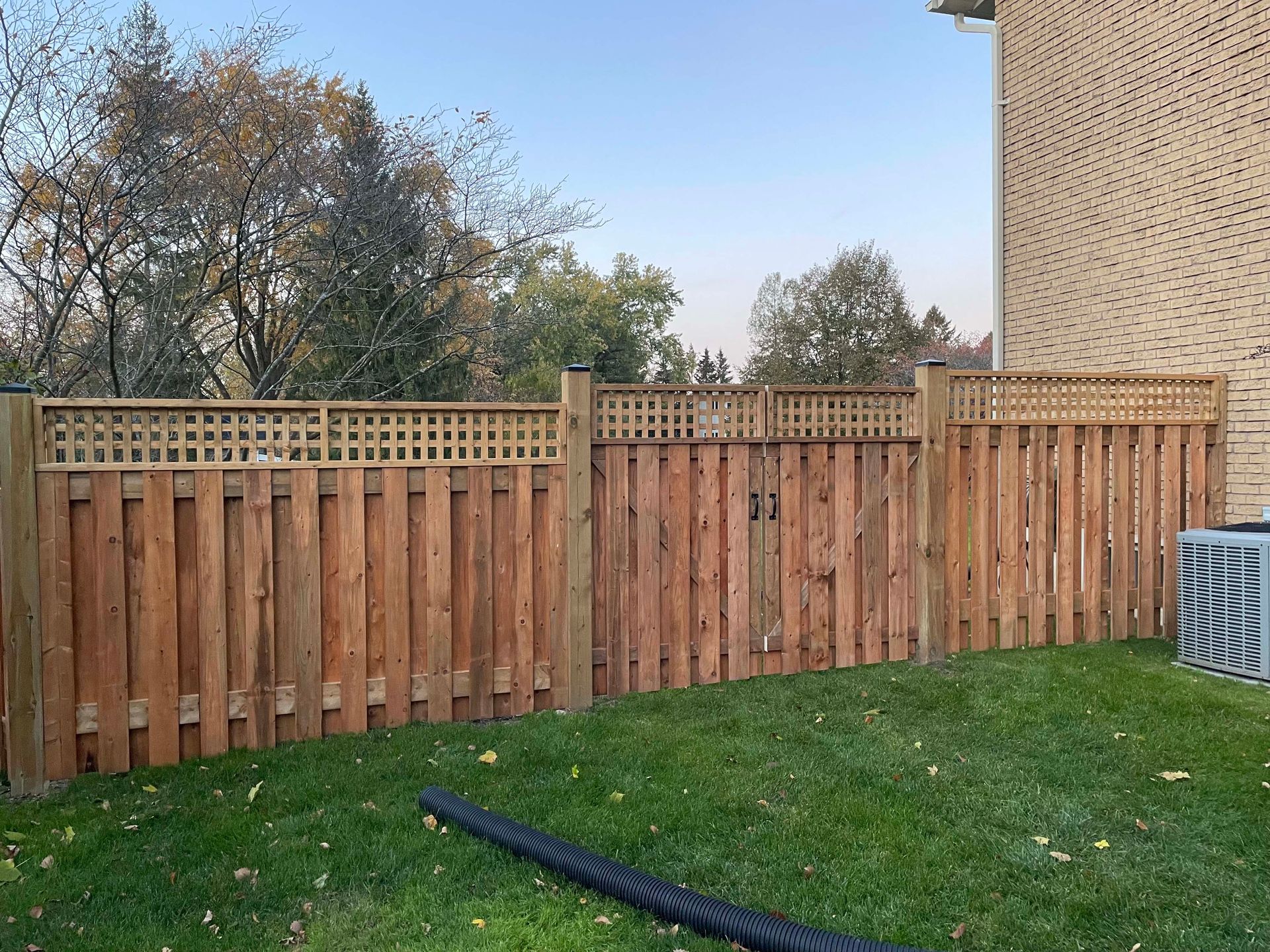 A wooden fence is in the backyard of a house.