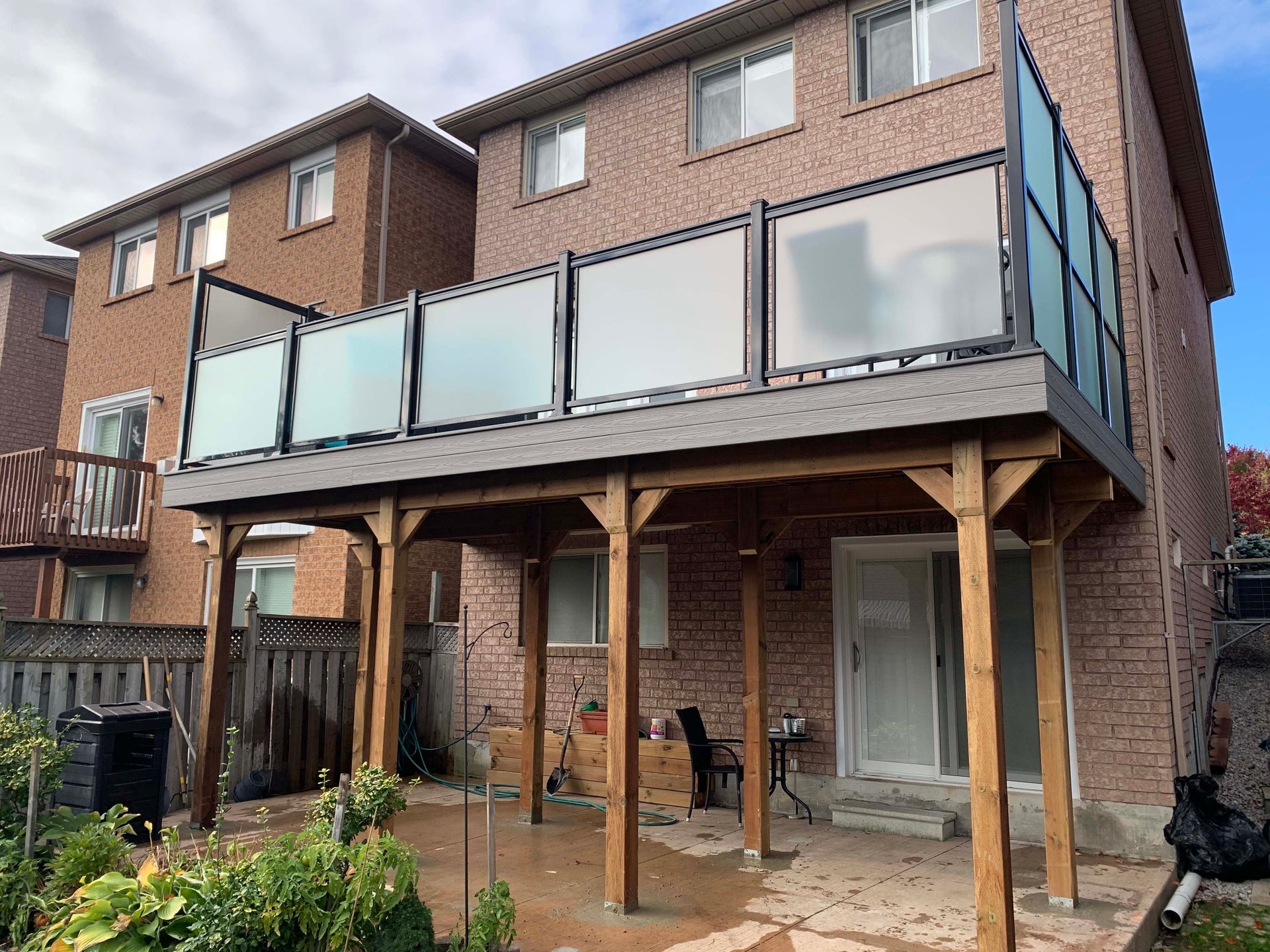 A large brick house with a wooden deck and a glass railing.
