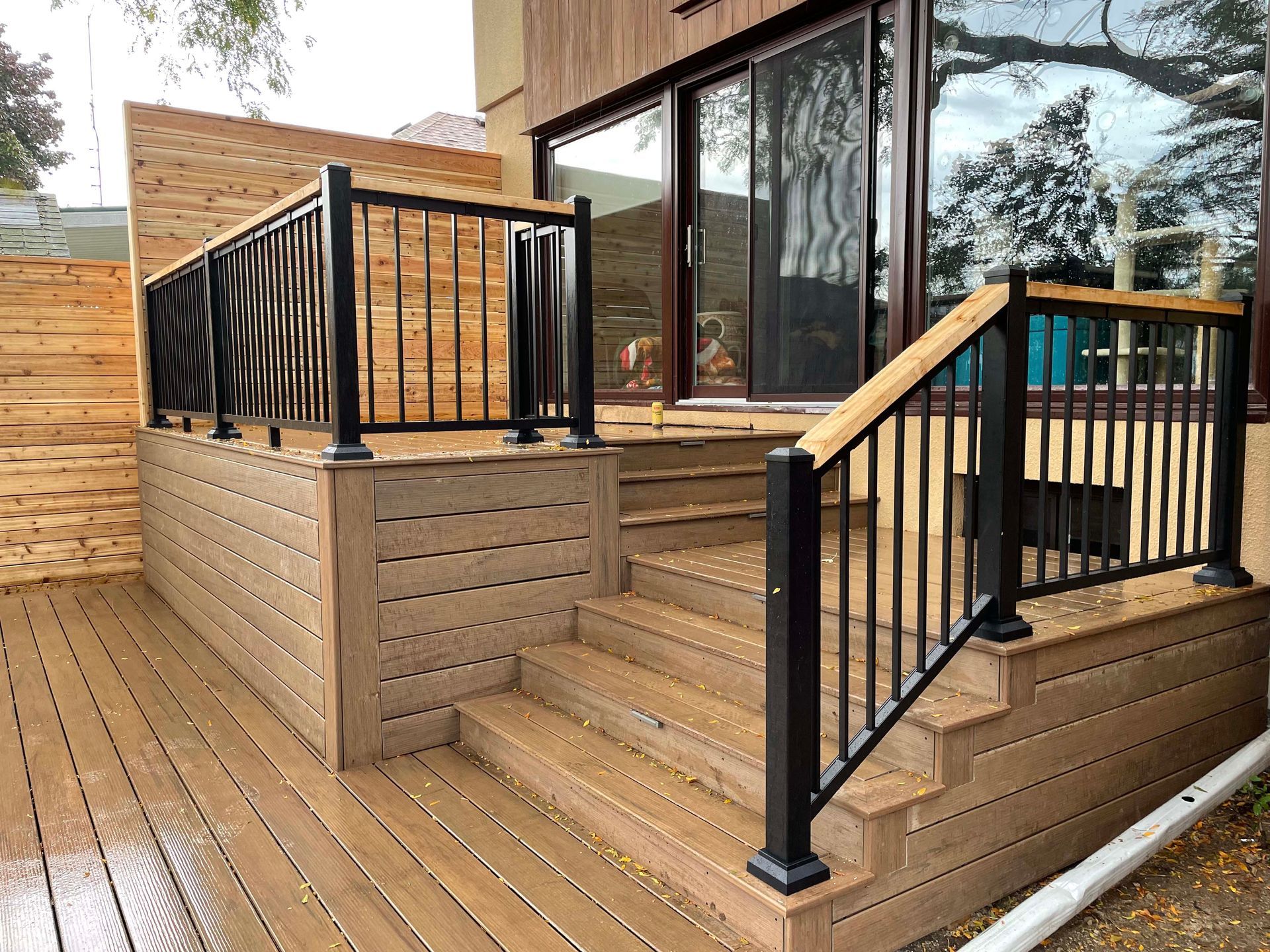 A wooden deck with stairs and a metal railing.