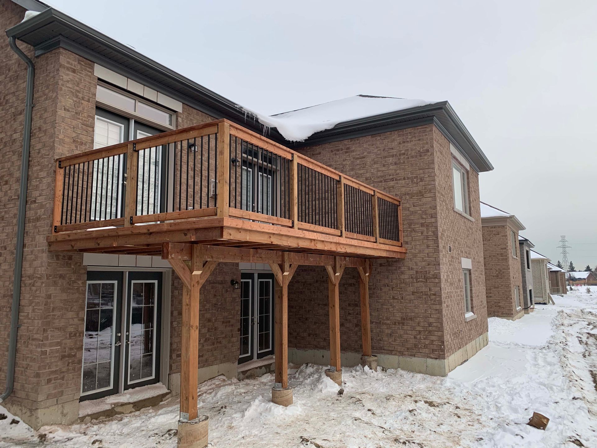 A large brick house with a wooden deck in the snow.