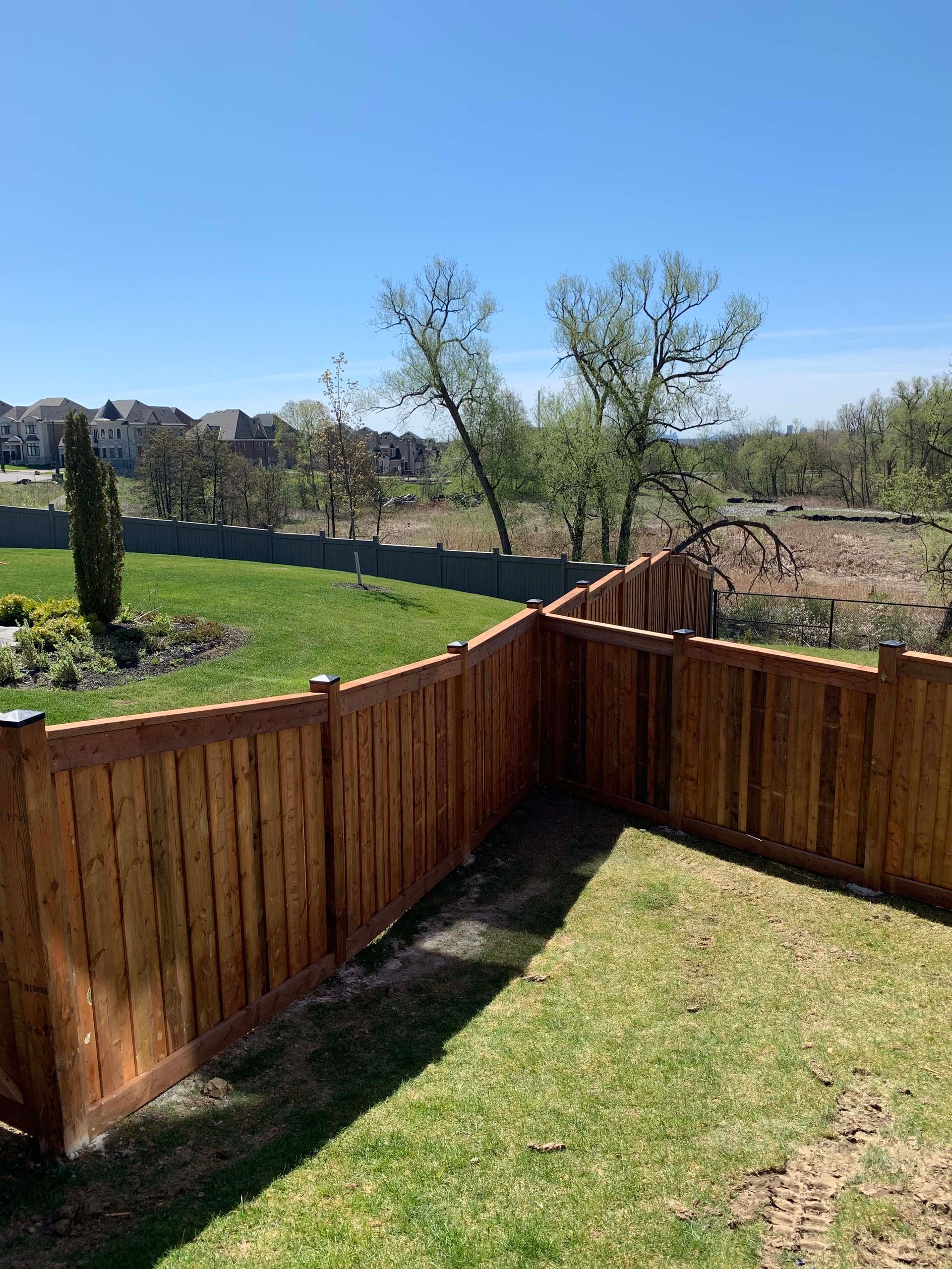 A wooden fence surrounds a lush green yard.