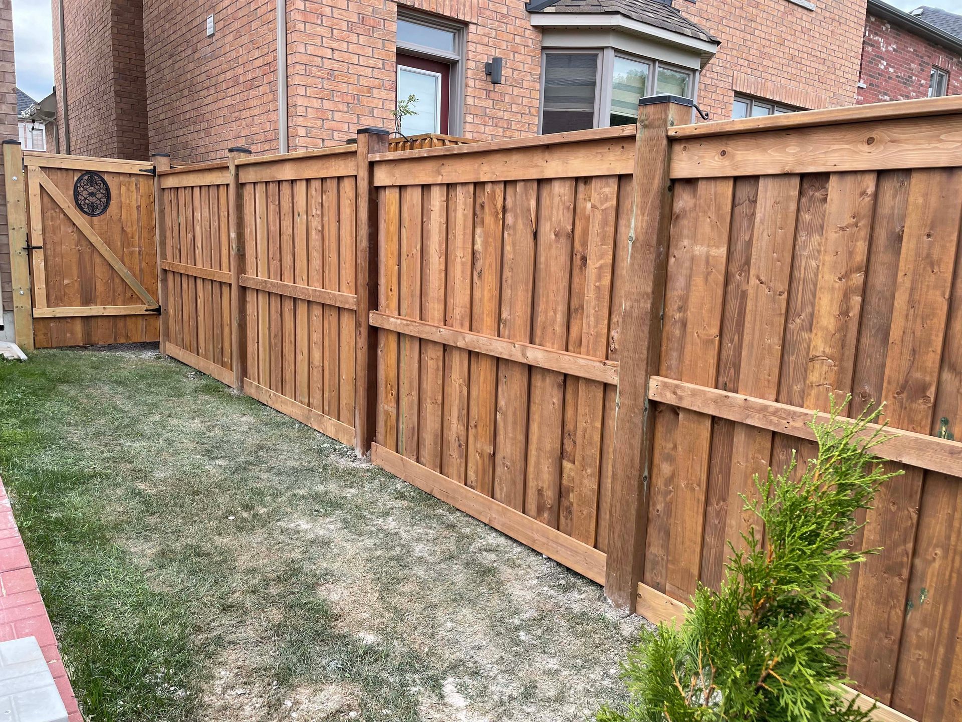 A wooden fence with a gate in the backyard of a house.