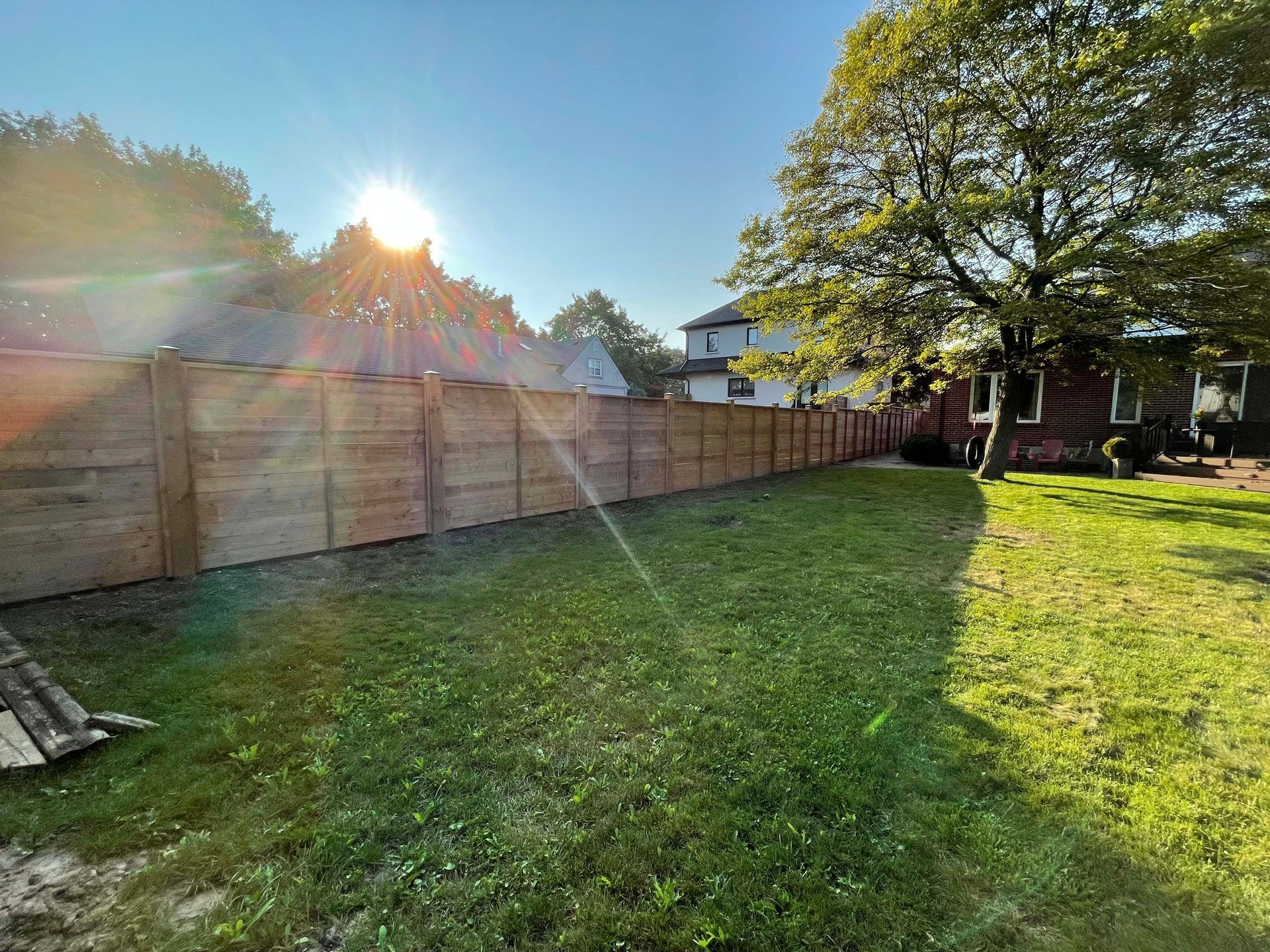 The sun is shining through the trees in the backyard of a house.