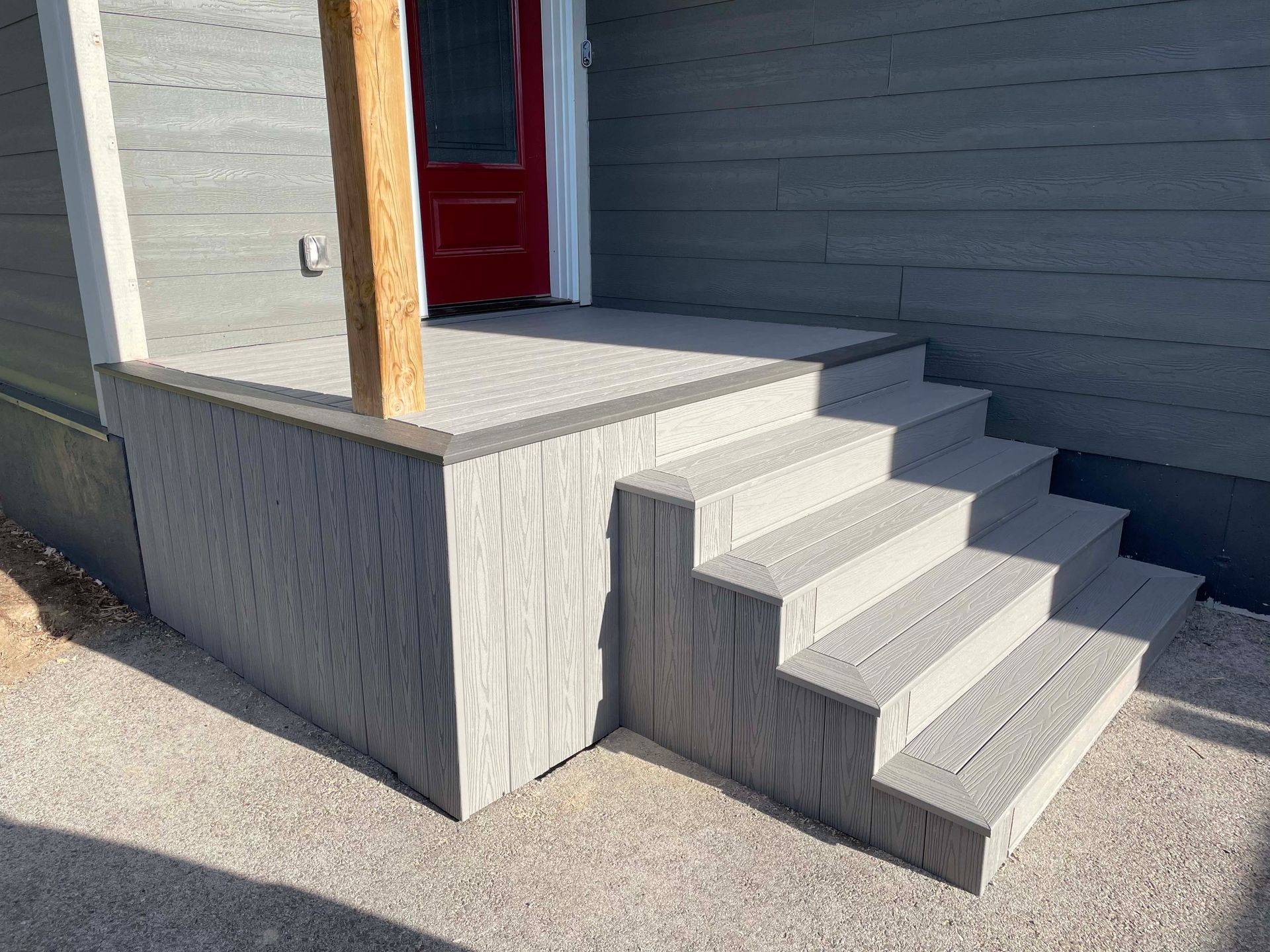 A porch with stairs leading up to it and a red door.