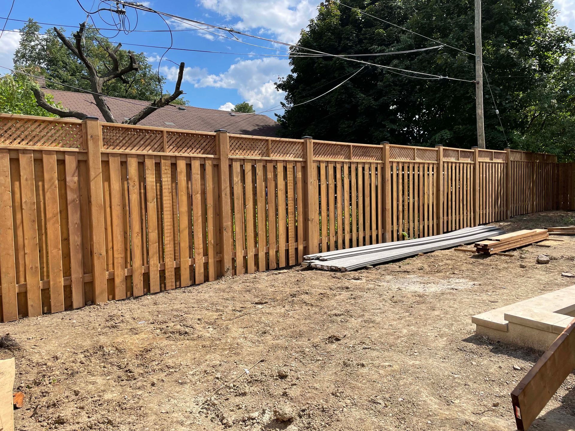 A wooden fence is being built in a backyard.