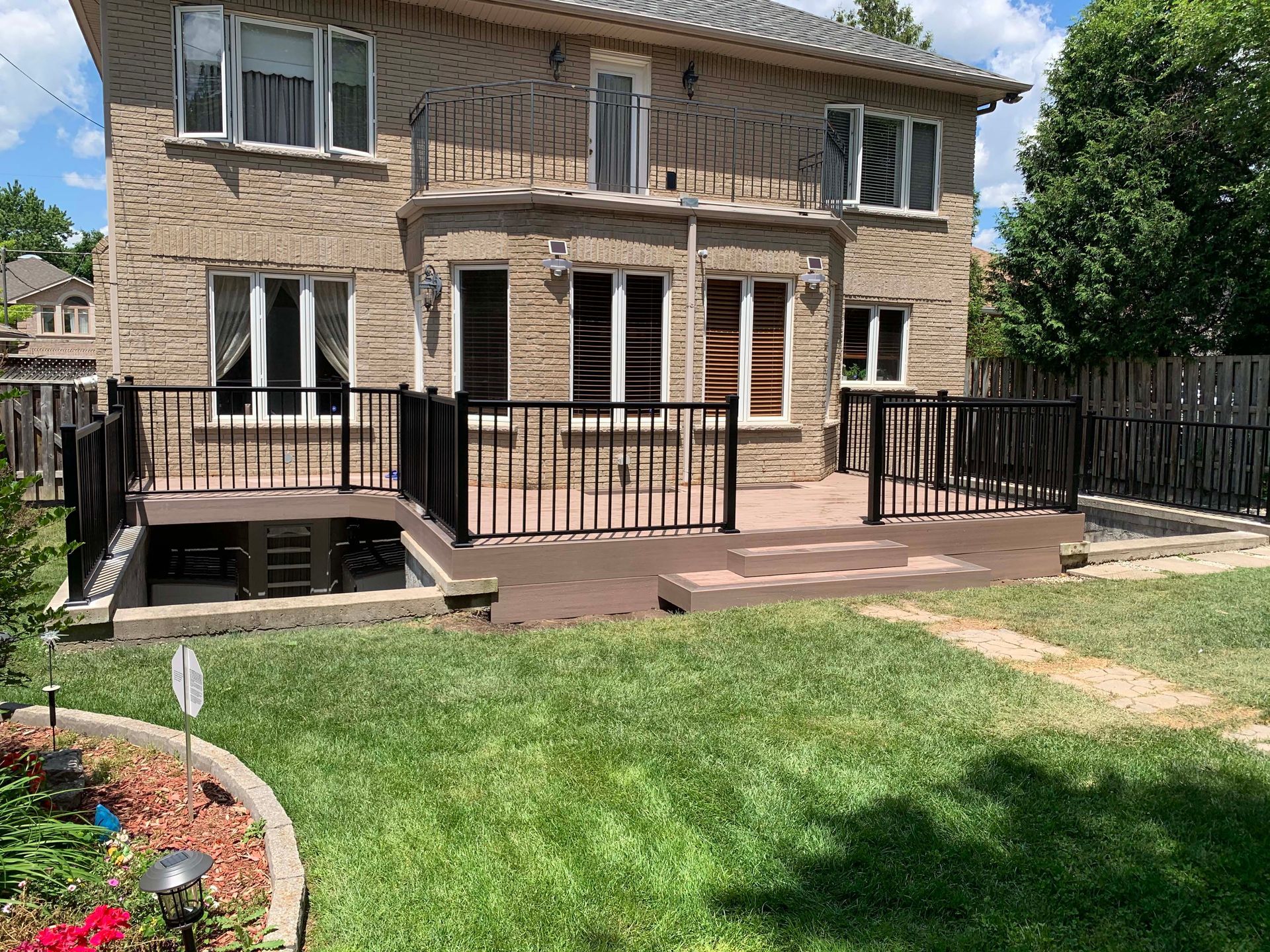 The backyard of a house with a deck and a fence.