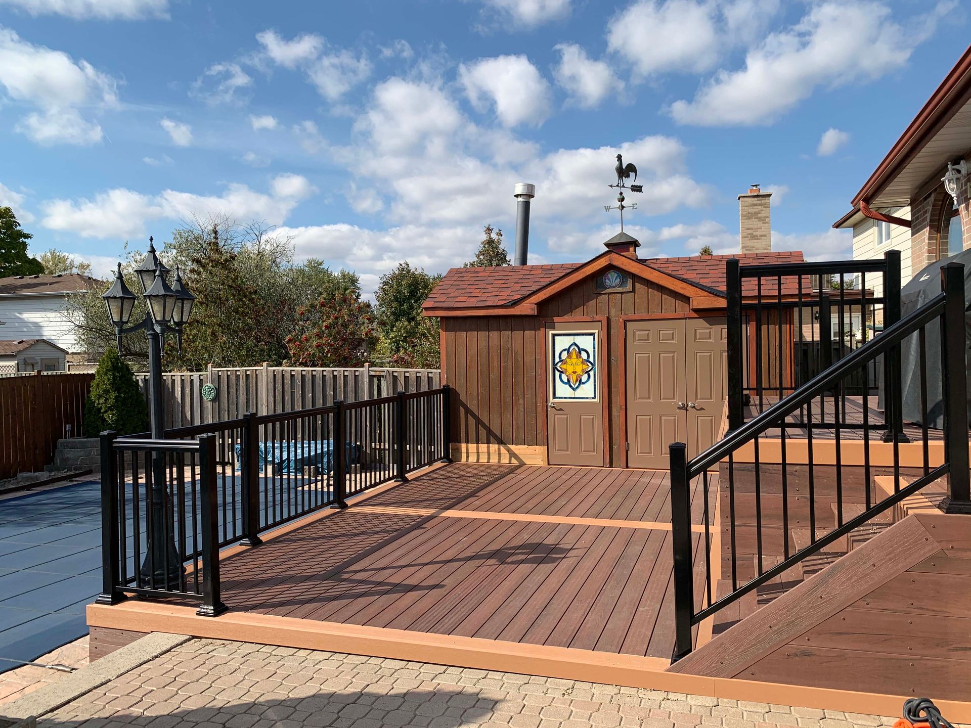 A wooden deck with stairs leading to a shed and a pool.