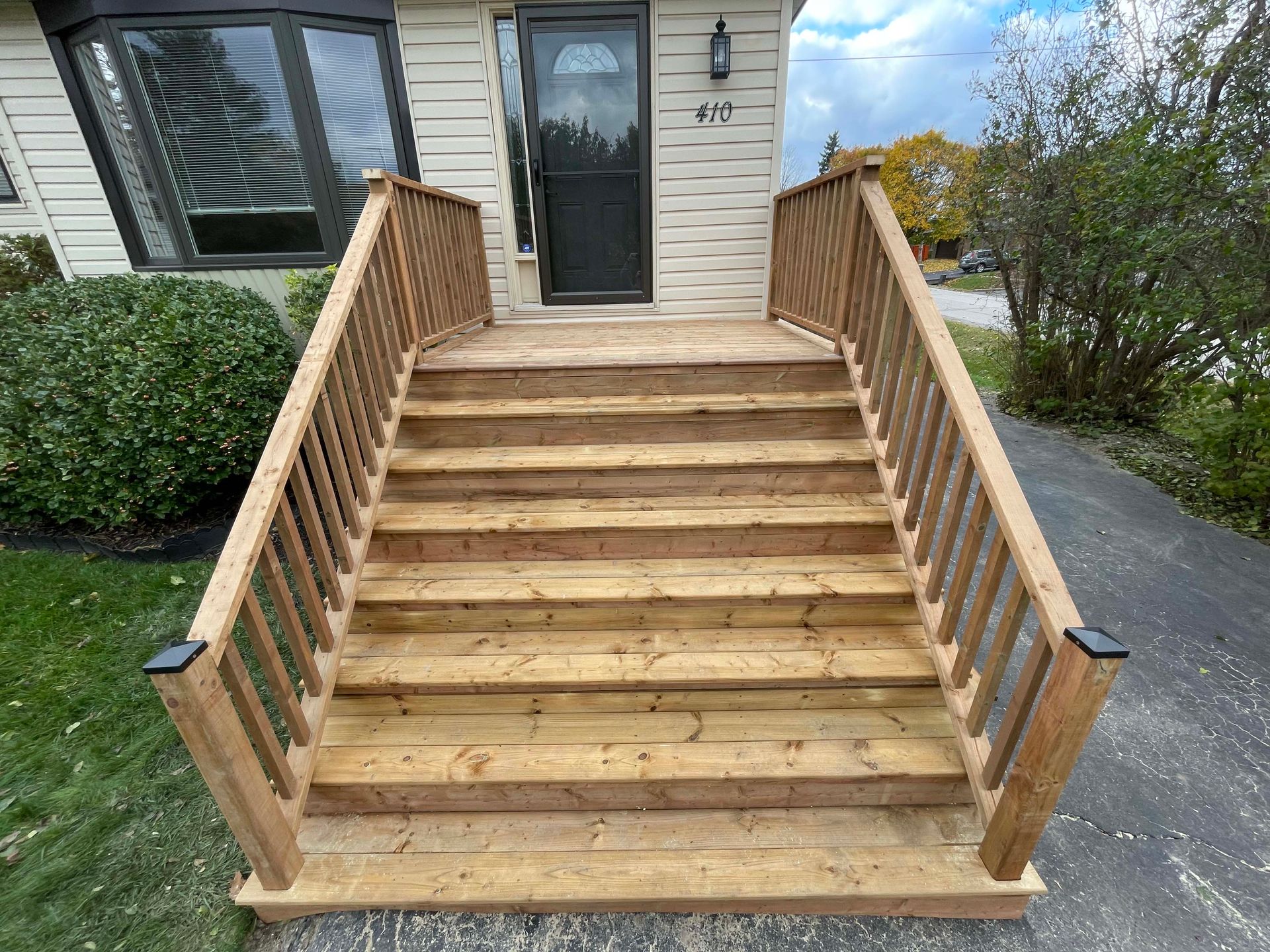 A wooden deck with stairs leading up to the front door of a house.