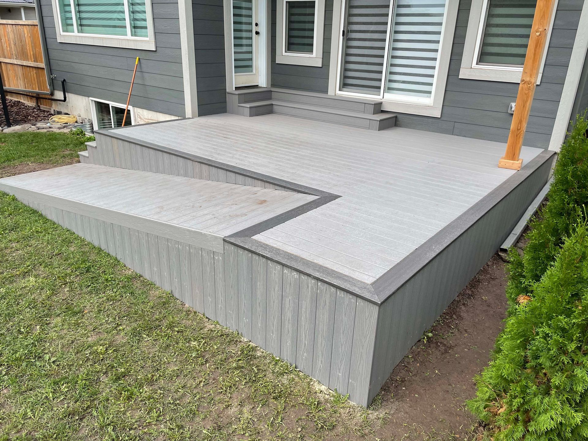 A gray house with a patio and stairs in front of it.