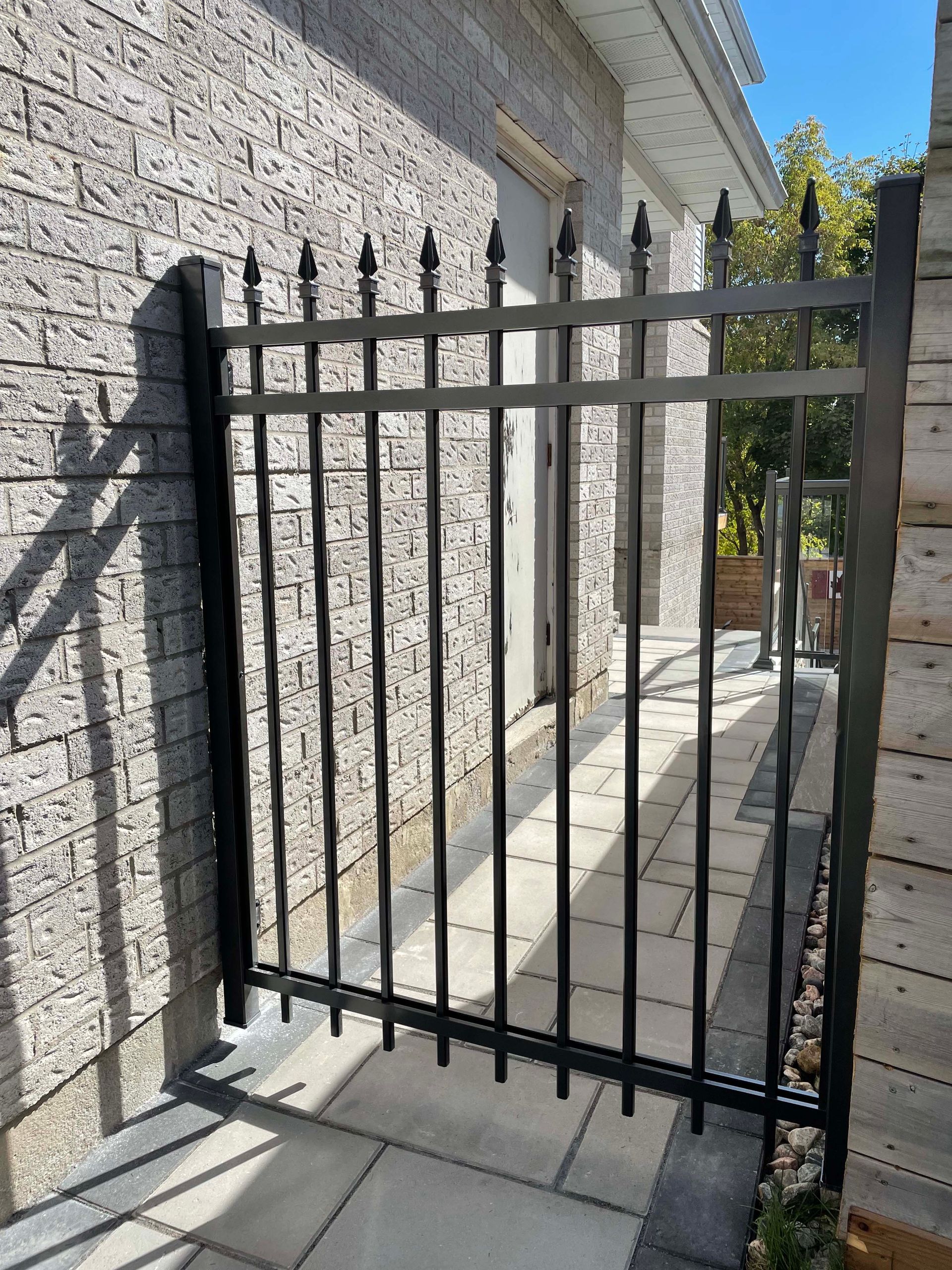 A black wrought iron gate is sitting next to a brick building.