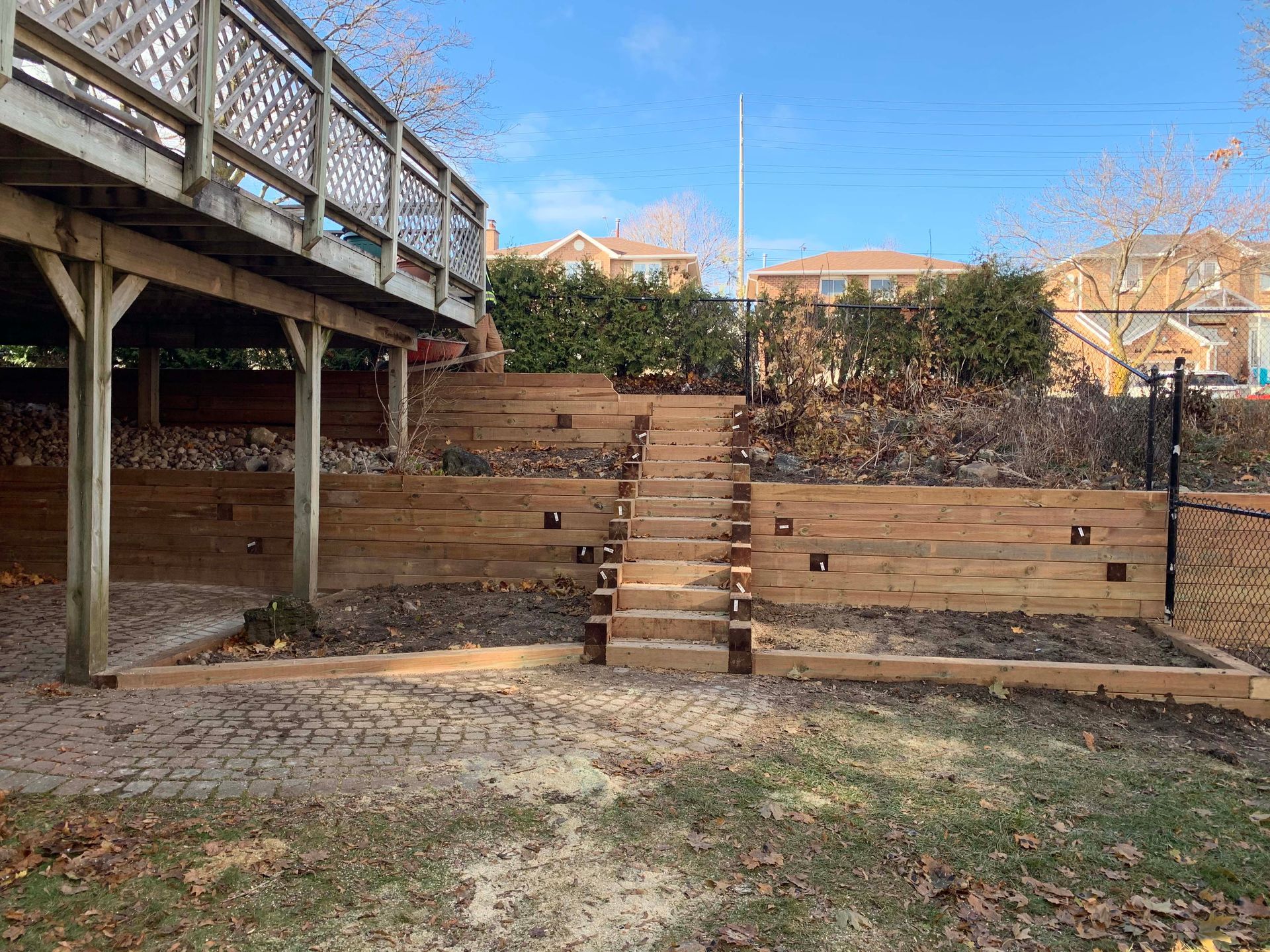 A wooden deck with stairs leading up to it in a backyard.