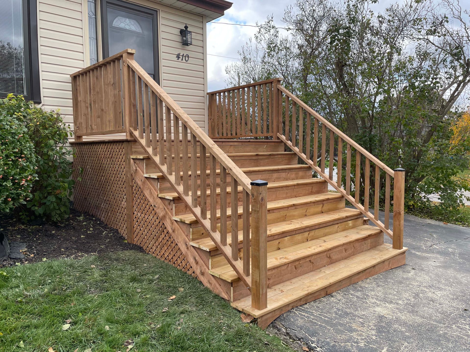 A wooden deck with stairs leading up to it is in front of a house.