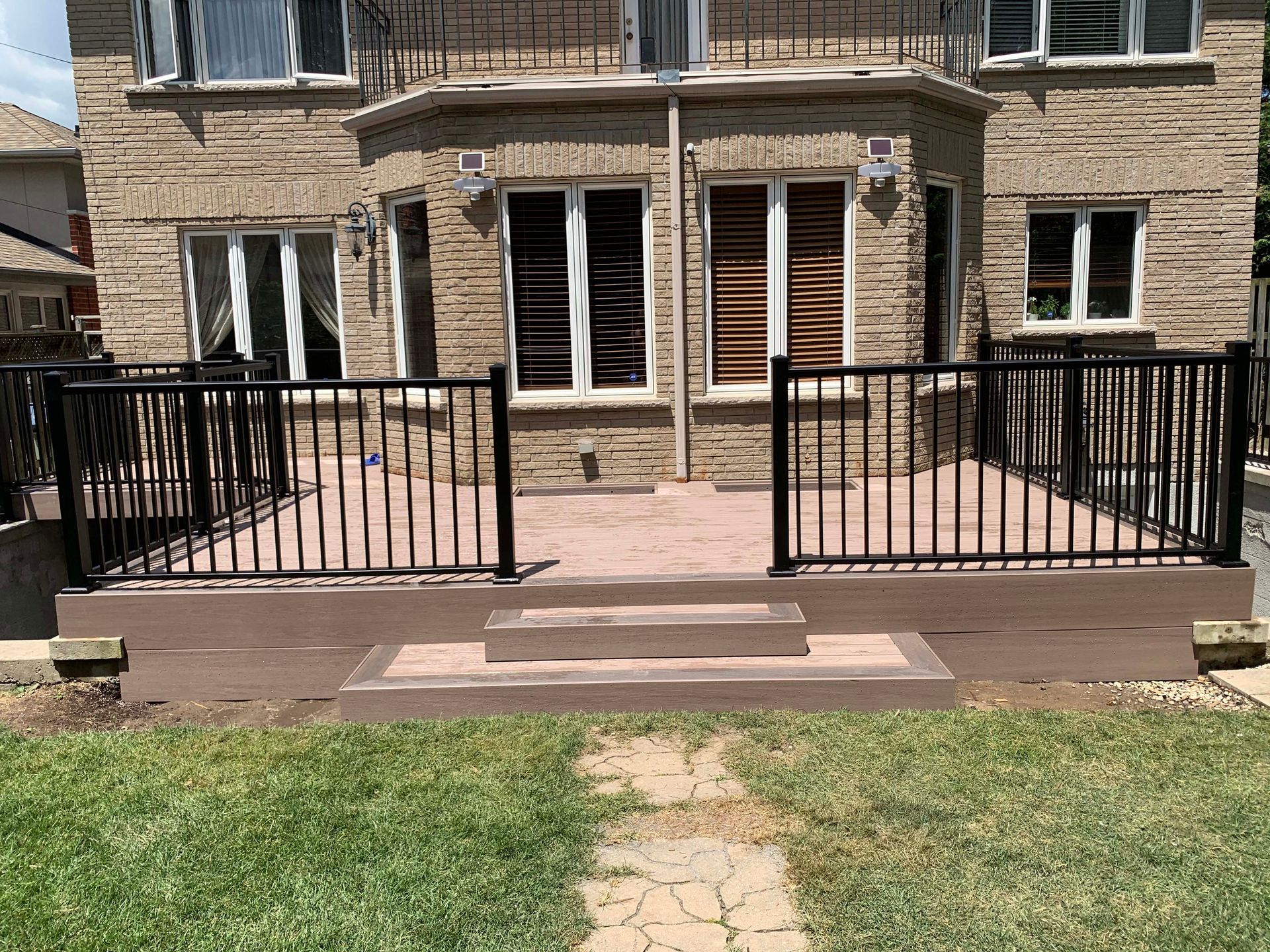 A brick house with a patio and stairs in front of it.