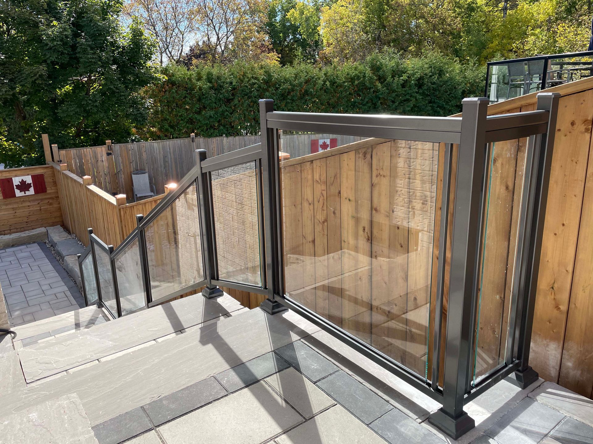 A staircase with a glass railing and a wooden fence behind it.
