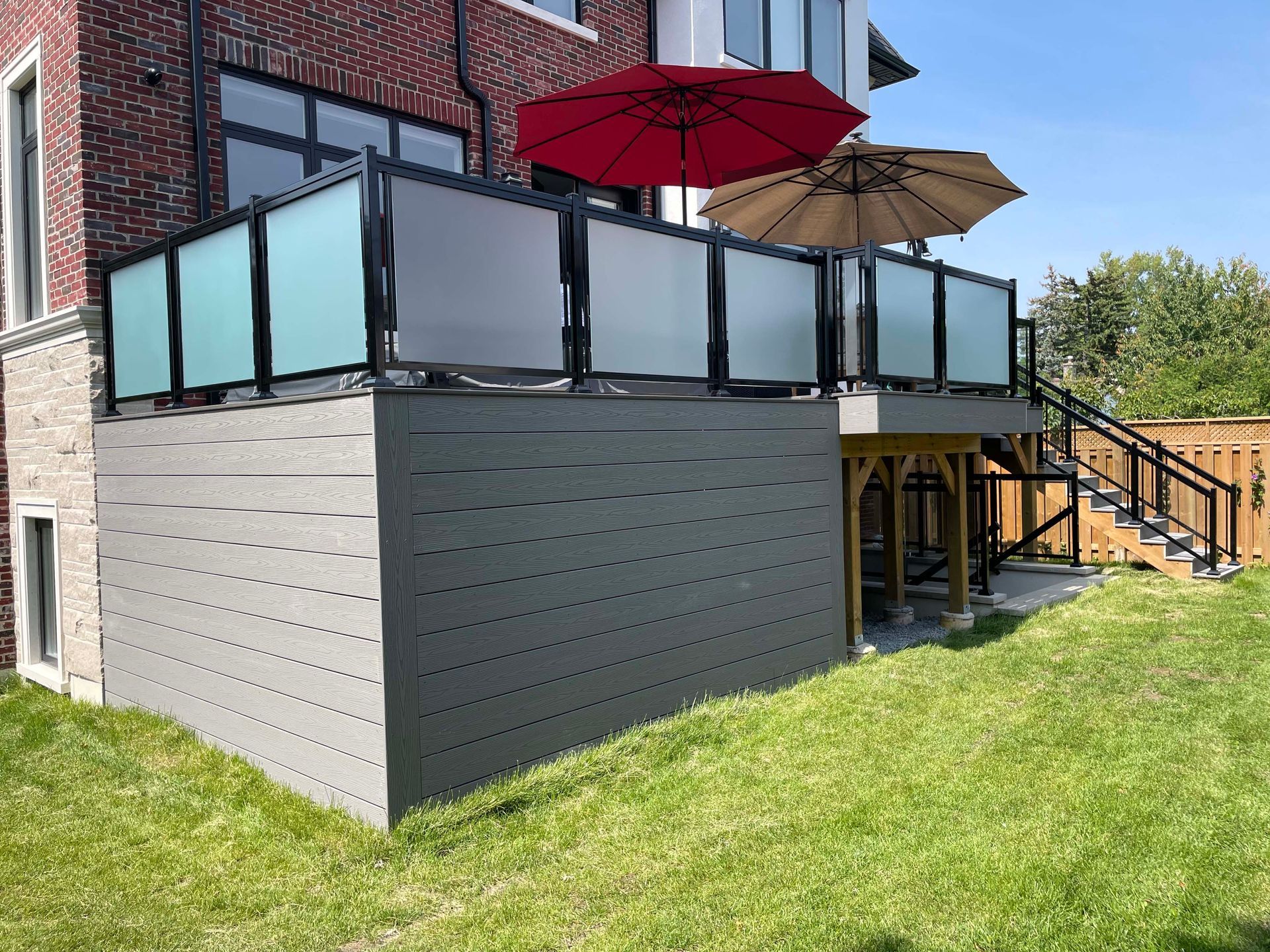 There are two umbrellas on the deck of a house.