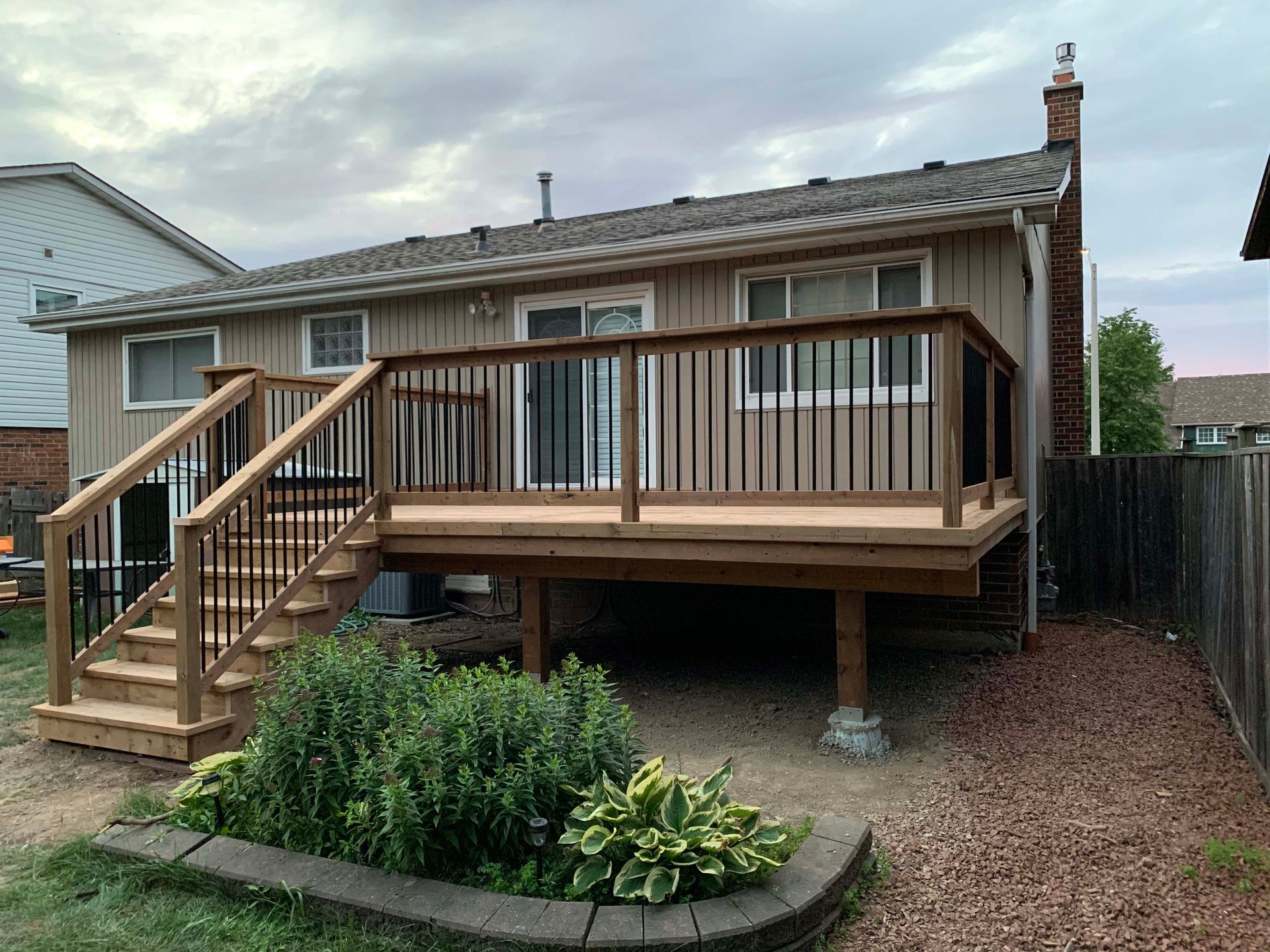 A house with a wooden deck and stairs in front of it.