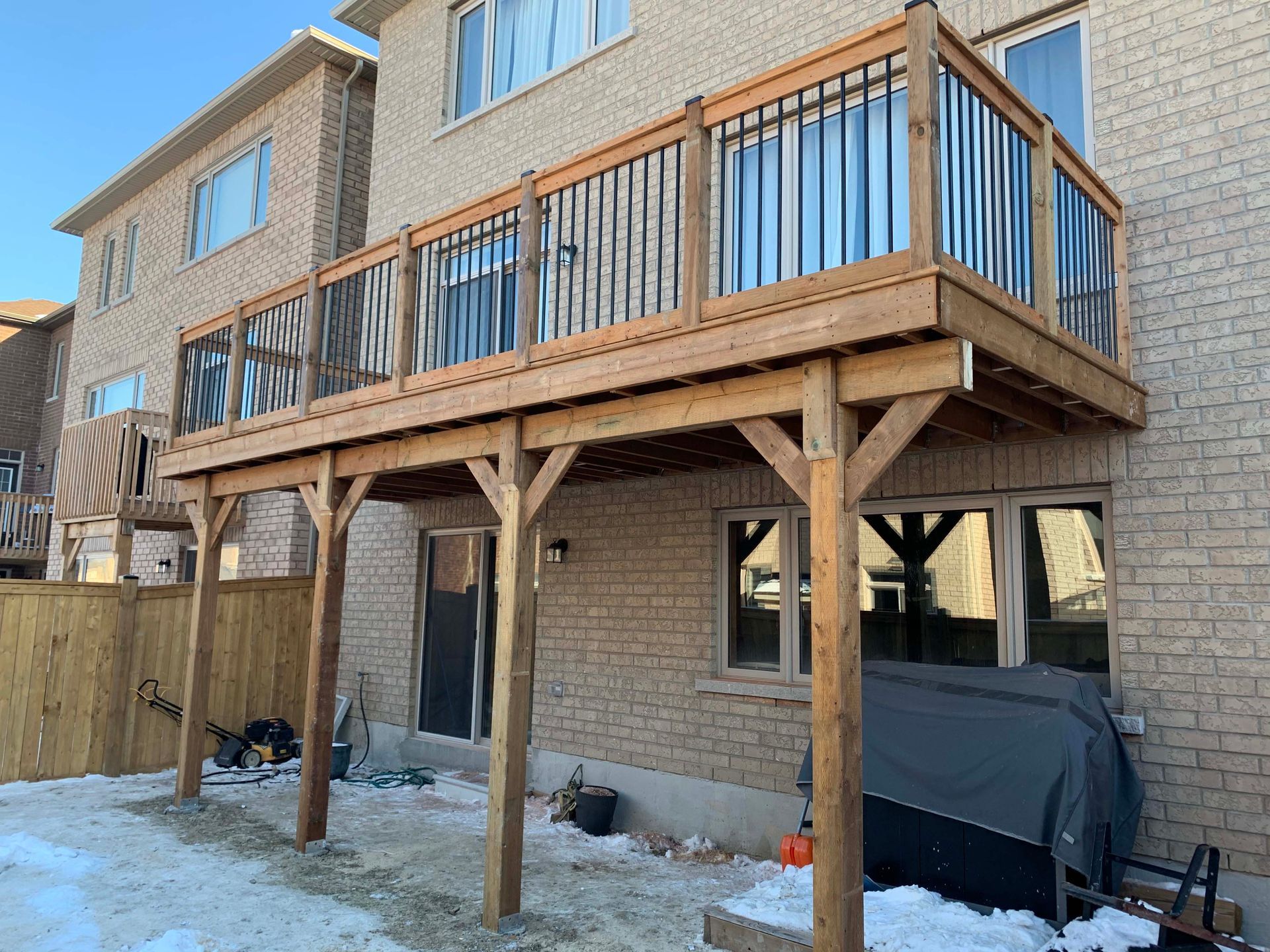 A large wooden deck is sitting underneath a brick house.