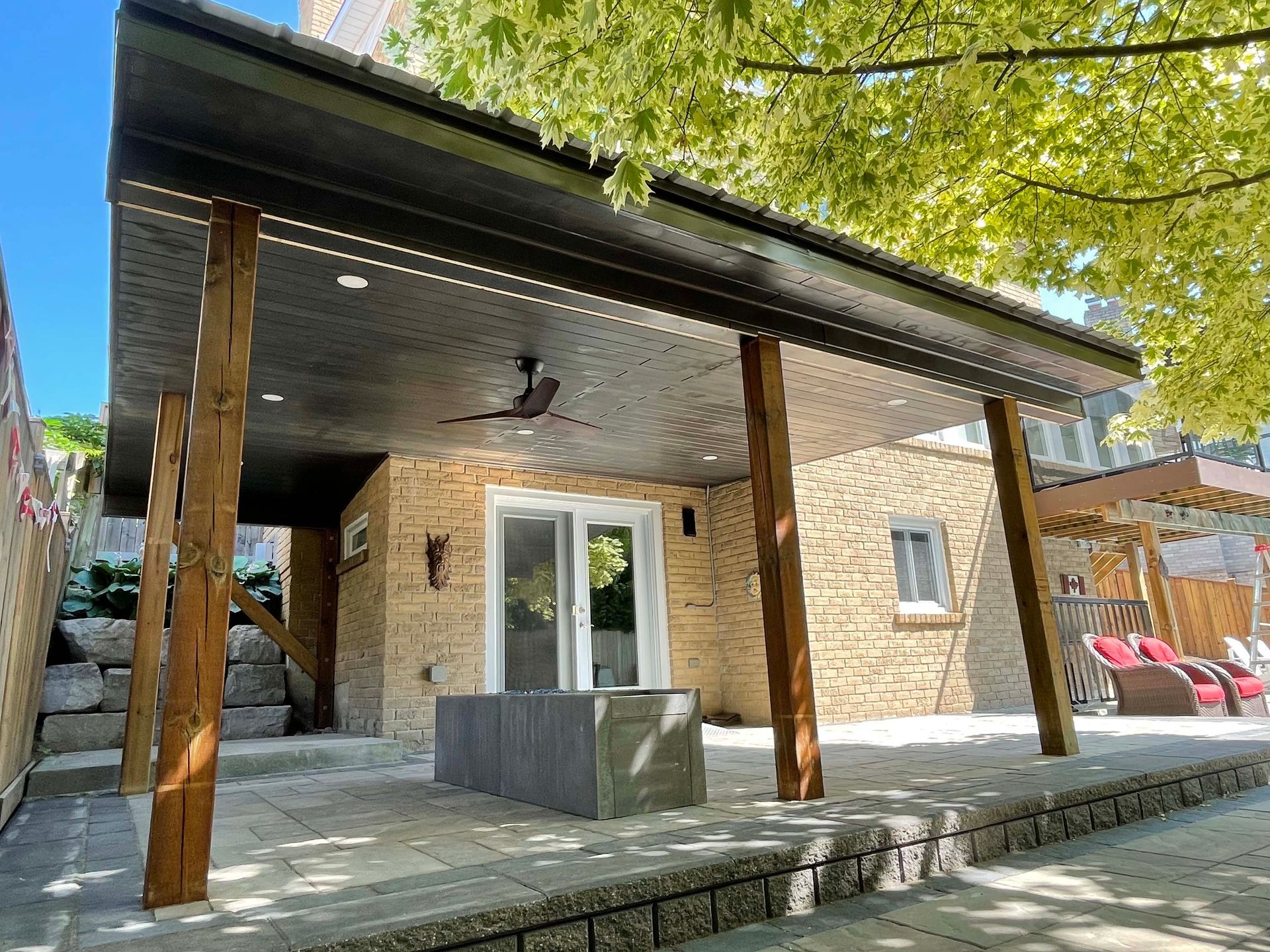 The backyard of a house with a covered patio and a ceiling fan.