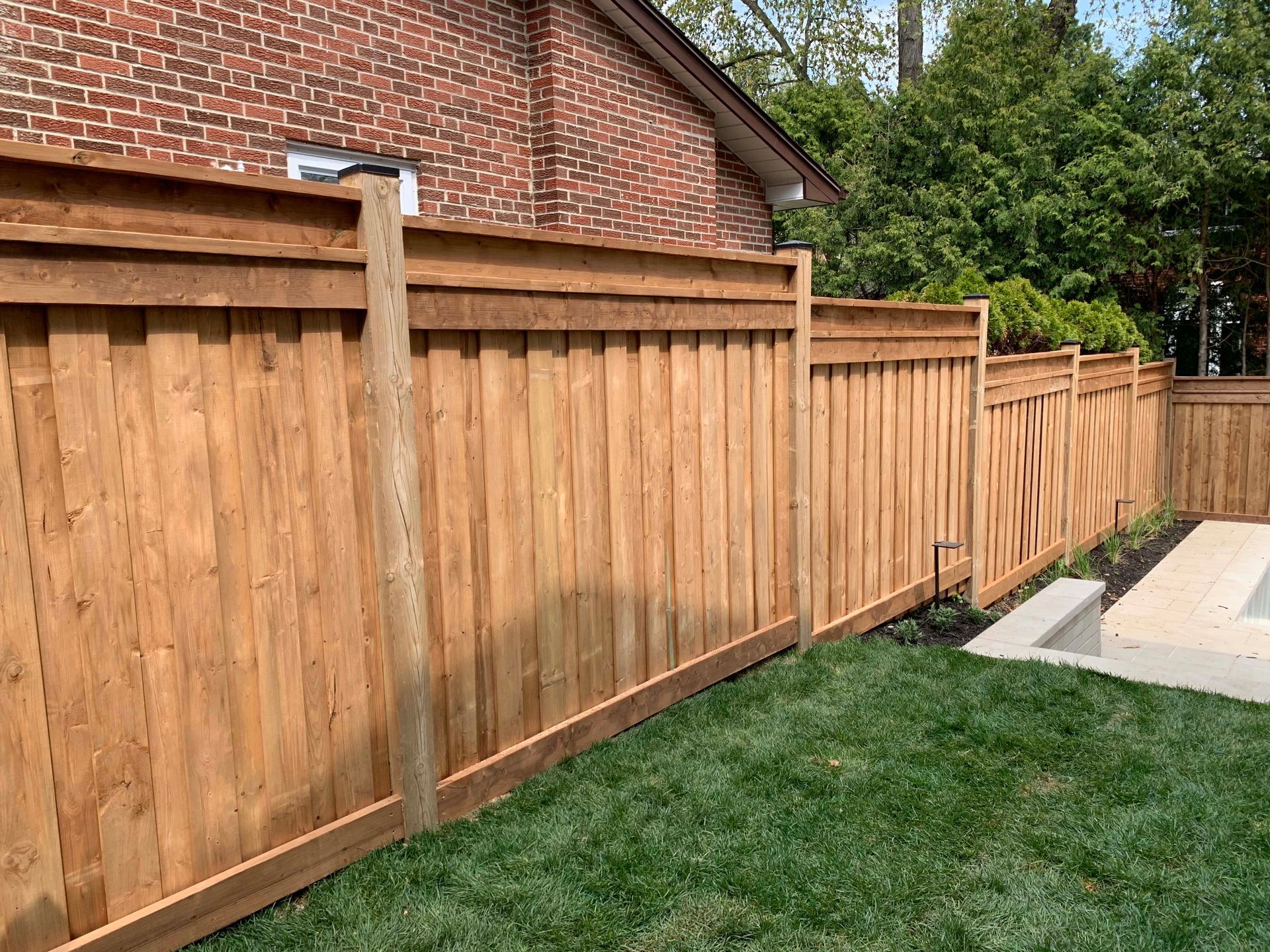 A wooden fence is in the backyard of a house.