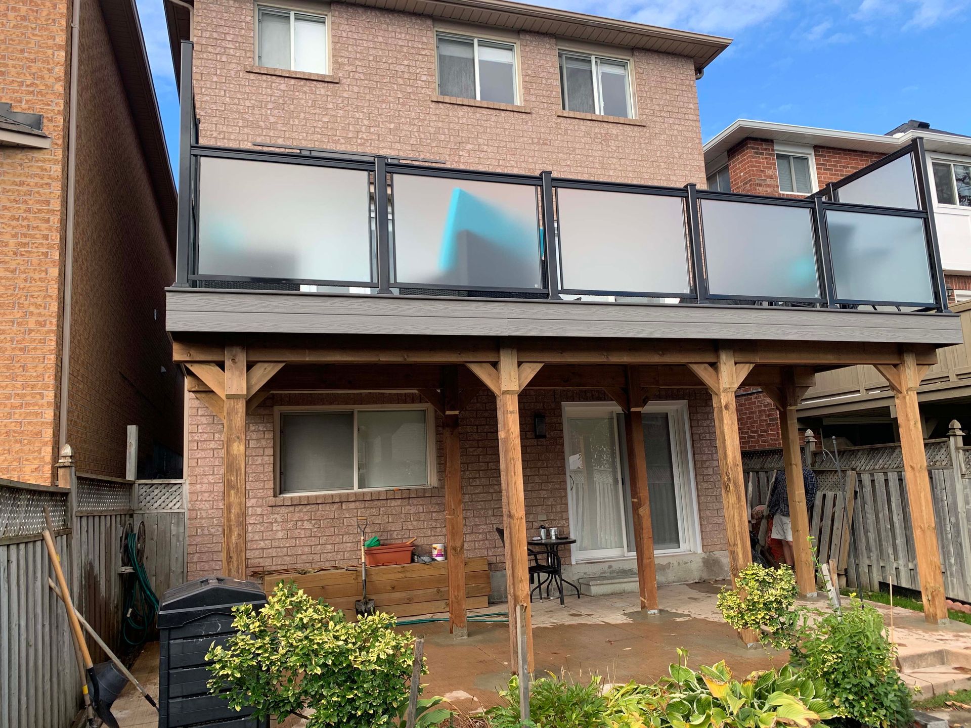 The back of a house with a large deck and a fence.