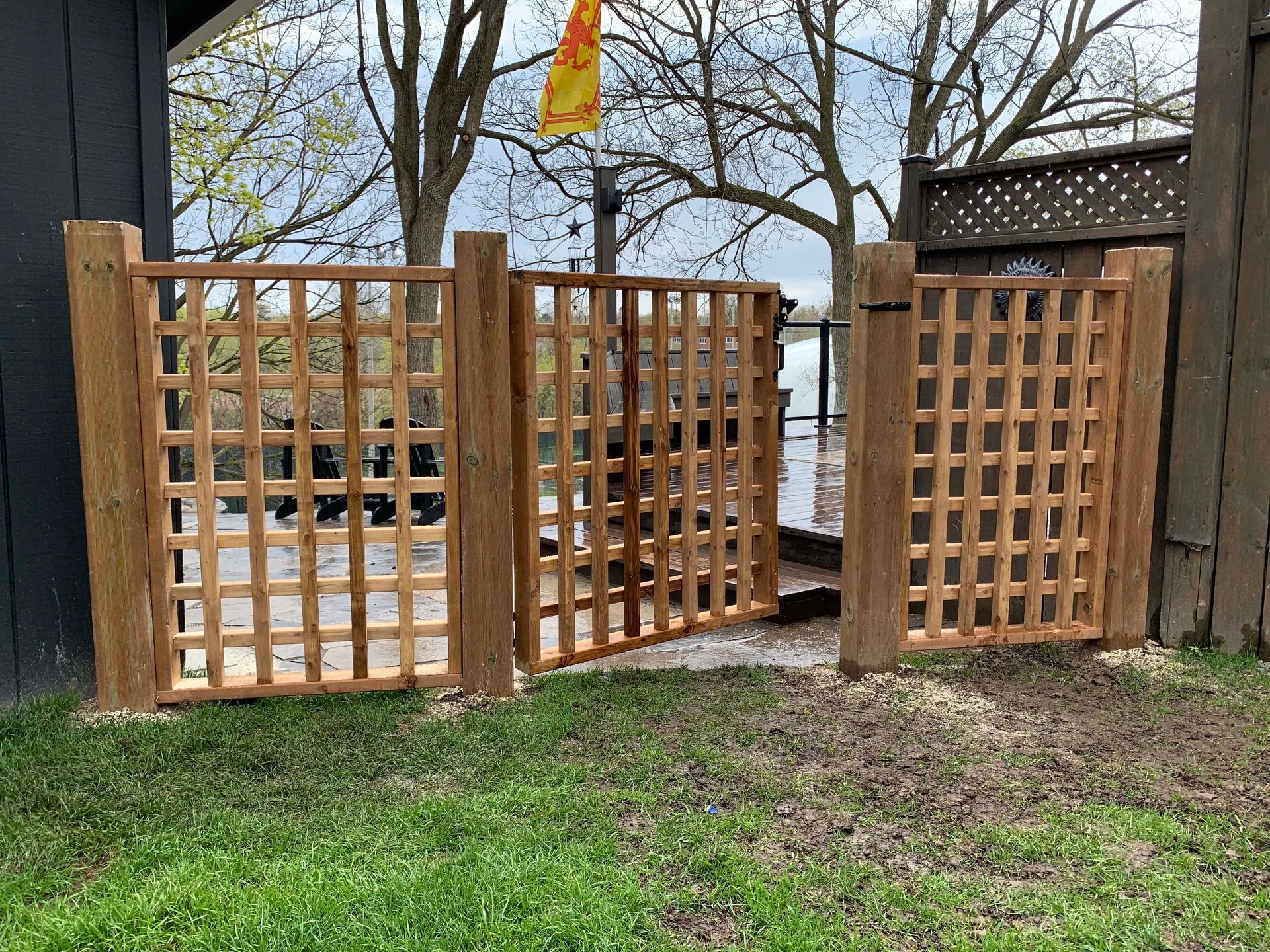 A wooden gate is sitting in the grass next to a wooden fence.