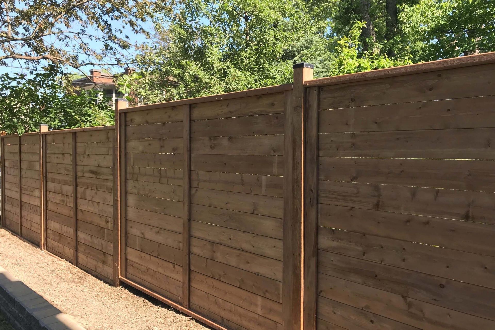 A wooden fence is surrounded by trees on a sunny day.