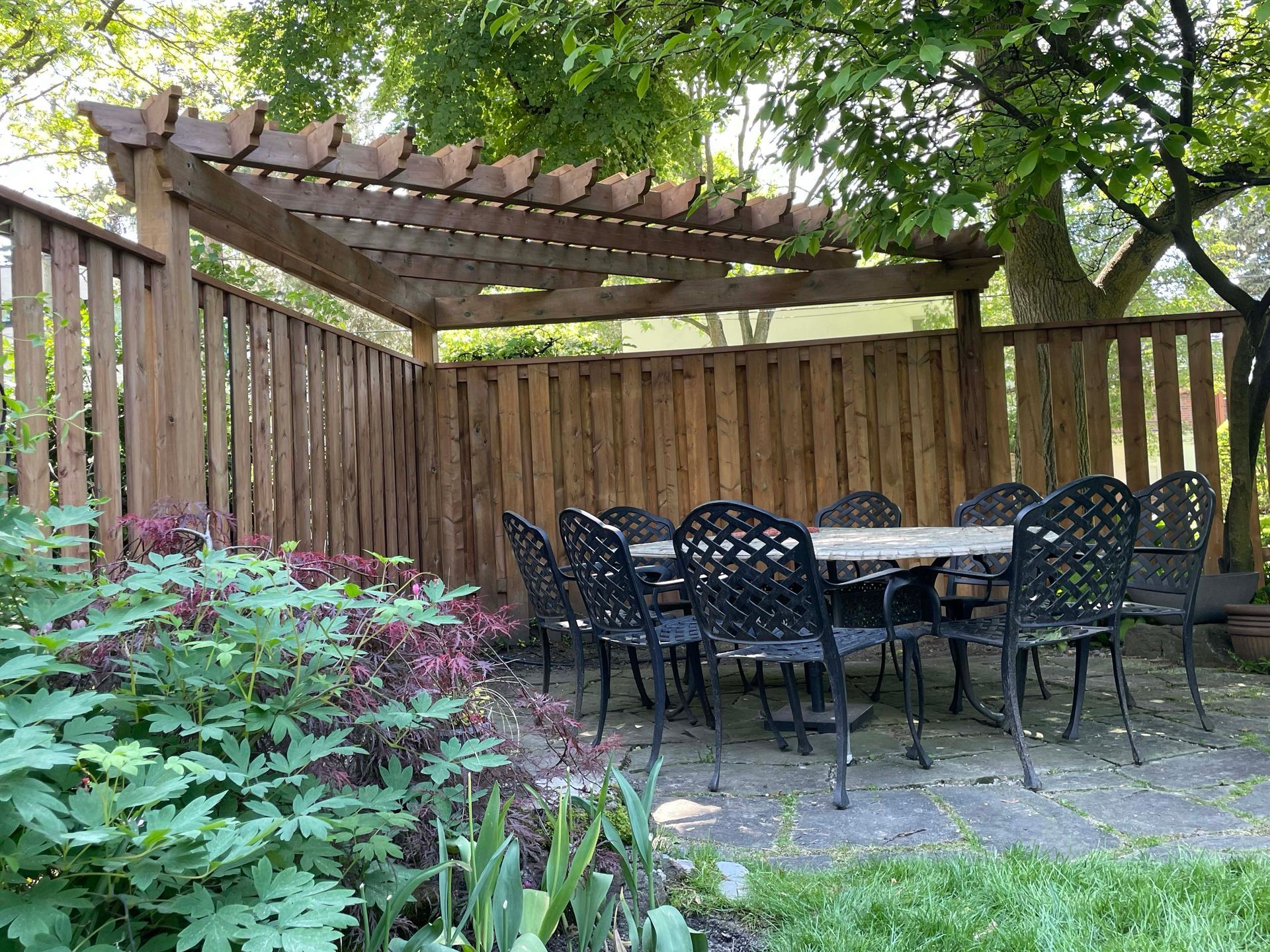 There is a table and chairs under a pergola in the backyard.