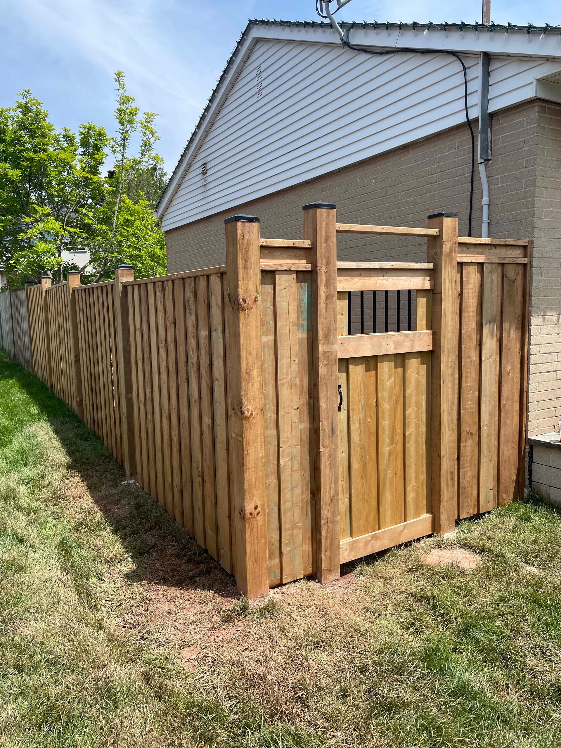 A wooden fence with a gate in the backyard of a house.
