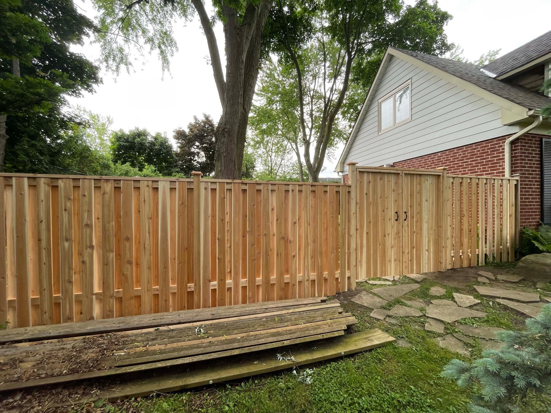A wooden fence is sitting in front of a brick house.