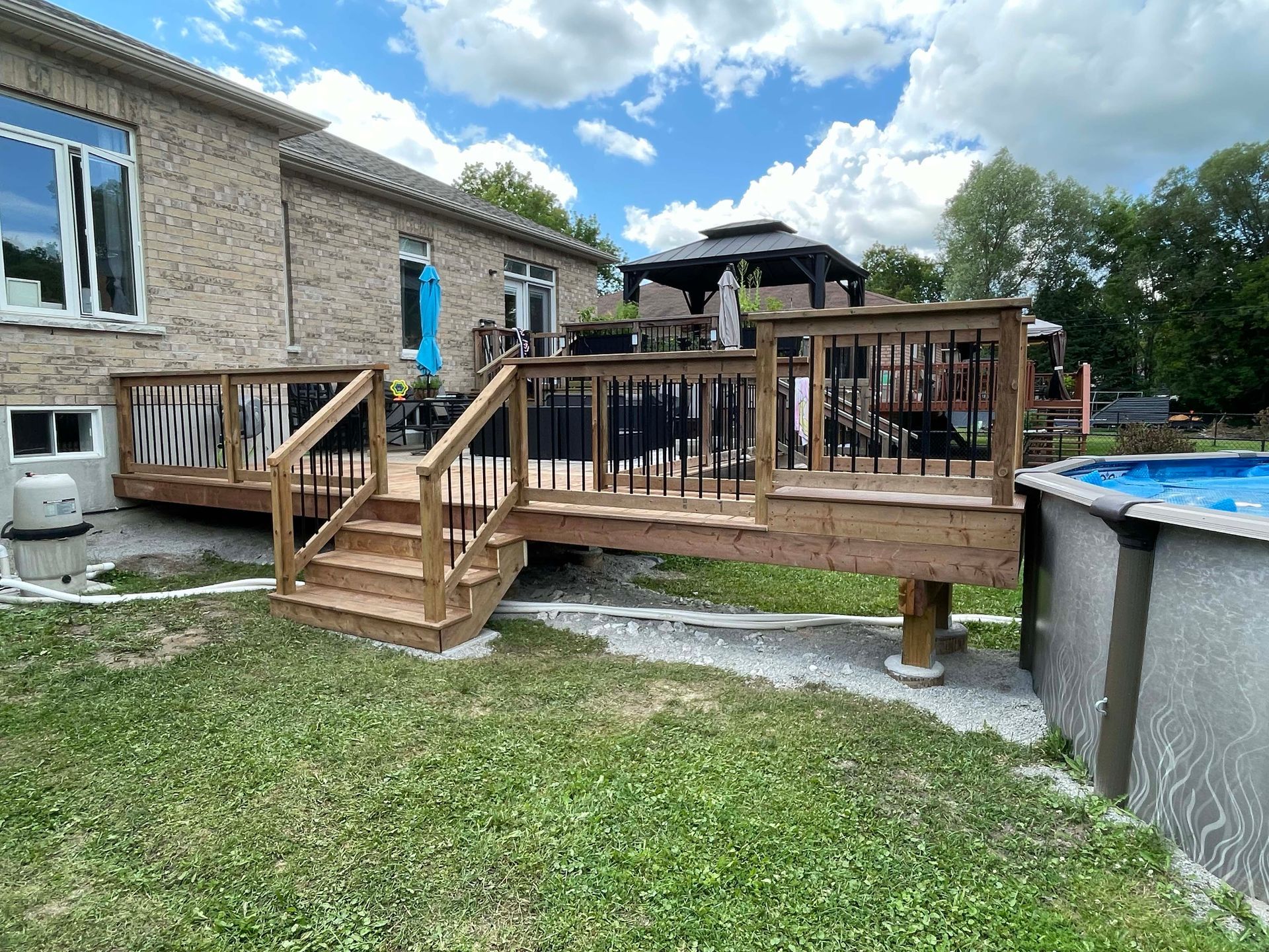 A wooden deck with stairs and a pool in the backyard of a house.