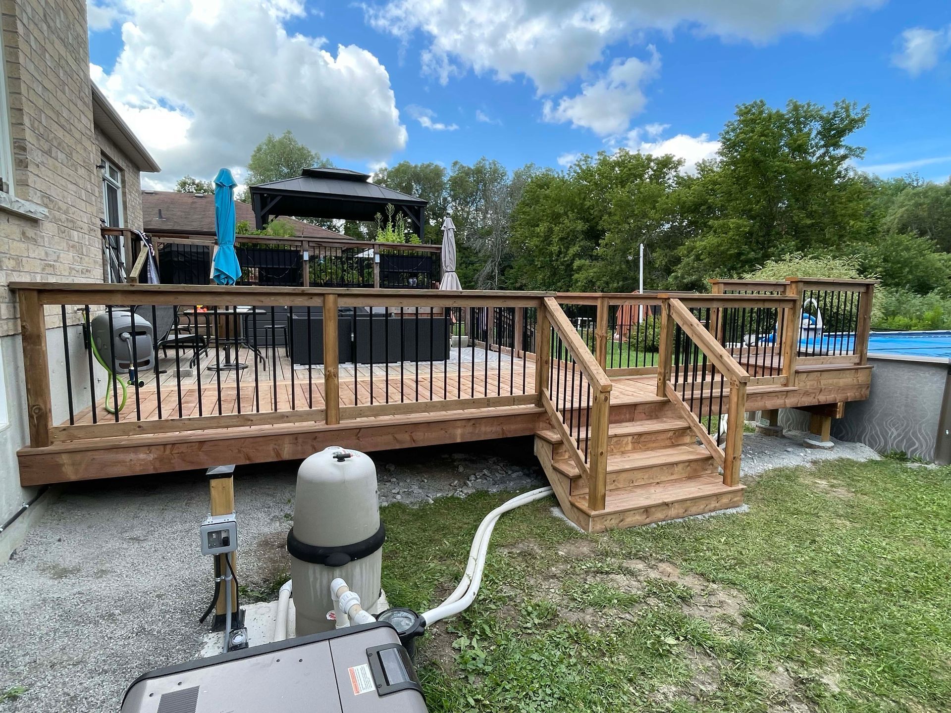 A wooden deck with stairs and a pool in the backyard.