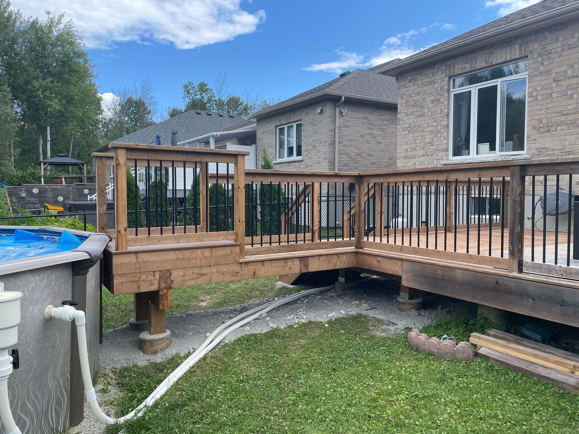 A wooden deck with a pool in the backyard of a house.