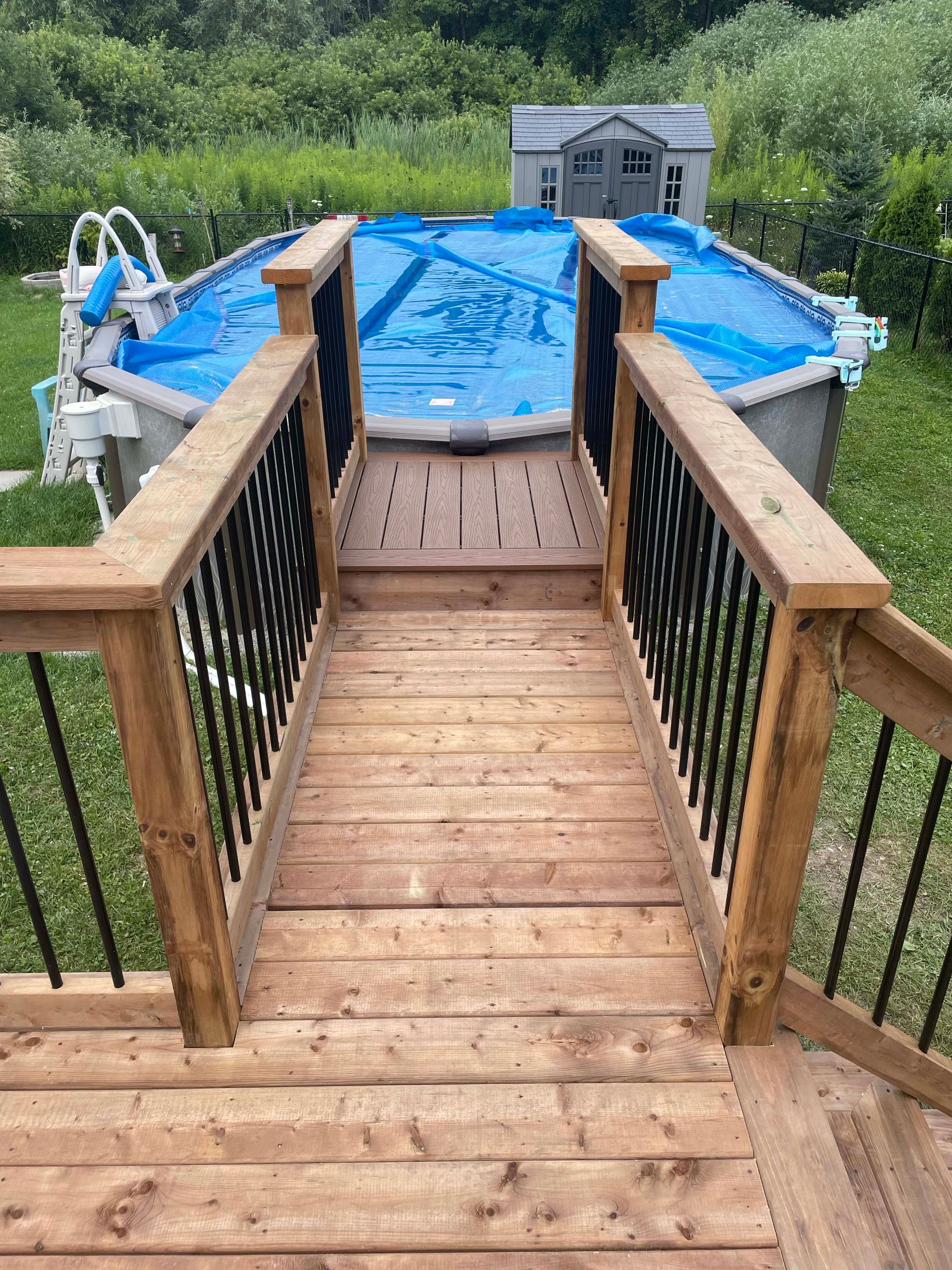 A wooden deck with stairs leading up to a swimming pool.