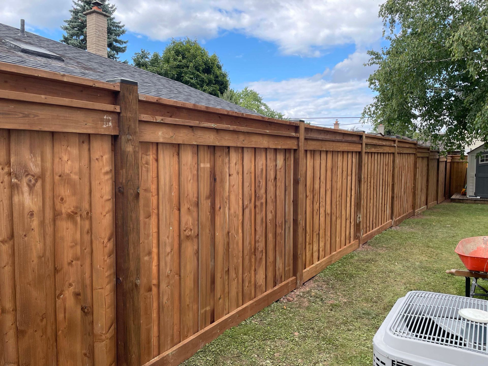 A wooden fence is in the backyard of a house.